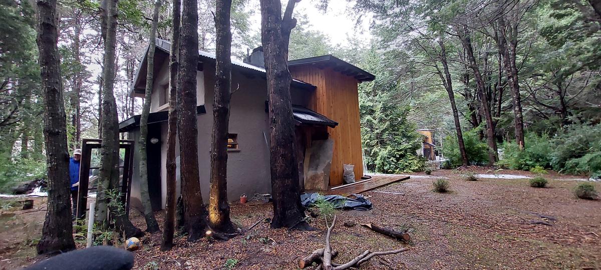 cabana rústica em floresta com fachada mista — projeto Cabañas Pruden - Bariloche, por ARM ARQUITECTOS, em San Carlos de Bariloche