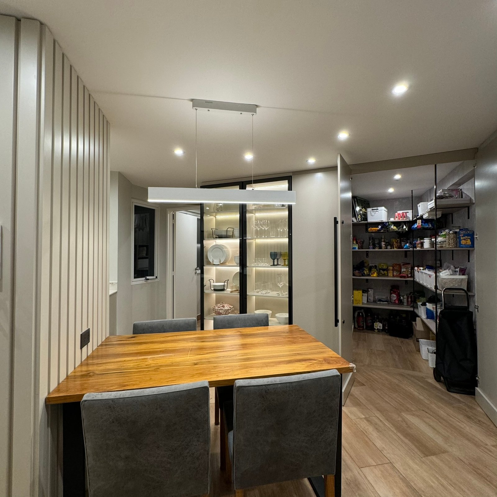 Comedor moderno con pared de lamas de madera y luz indirecta — proyecto Las Heras, por MDBK Arquitectura, en Palermo