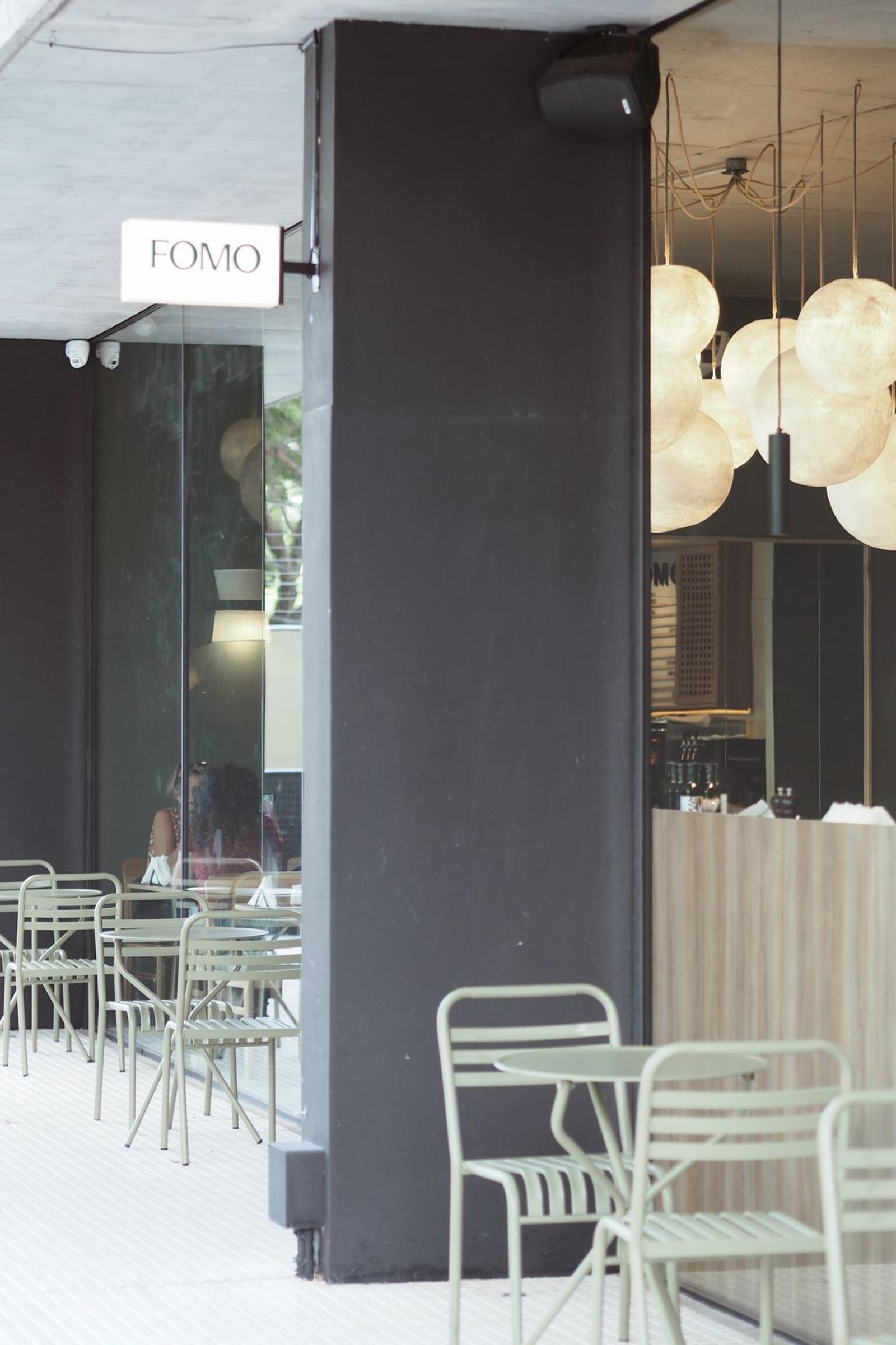 Fachada moderna con mesas y sillas de metal al aire libre, luces esféricas — proyecto FOMO CAFÉ, por APATHEIA, en Vicente López