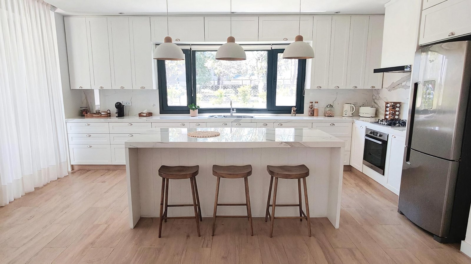 Cocina moderna estilo nórdico con isla central y taburetes — proyecto Casa MC, por Hermann Arquitectos, en Bv. Central