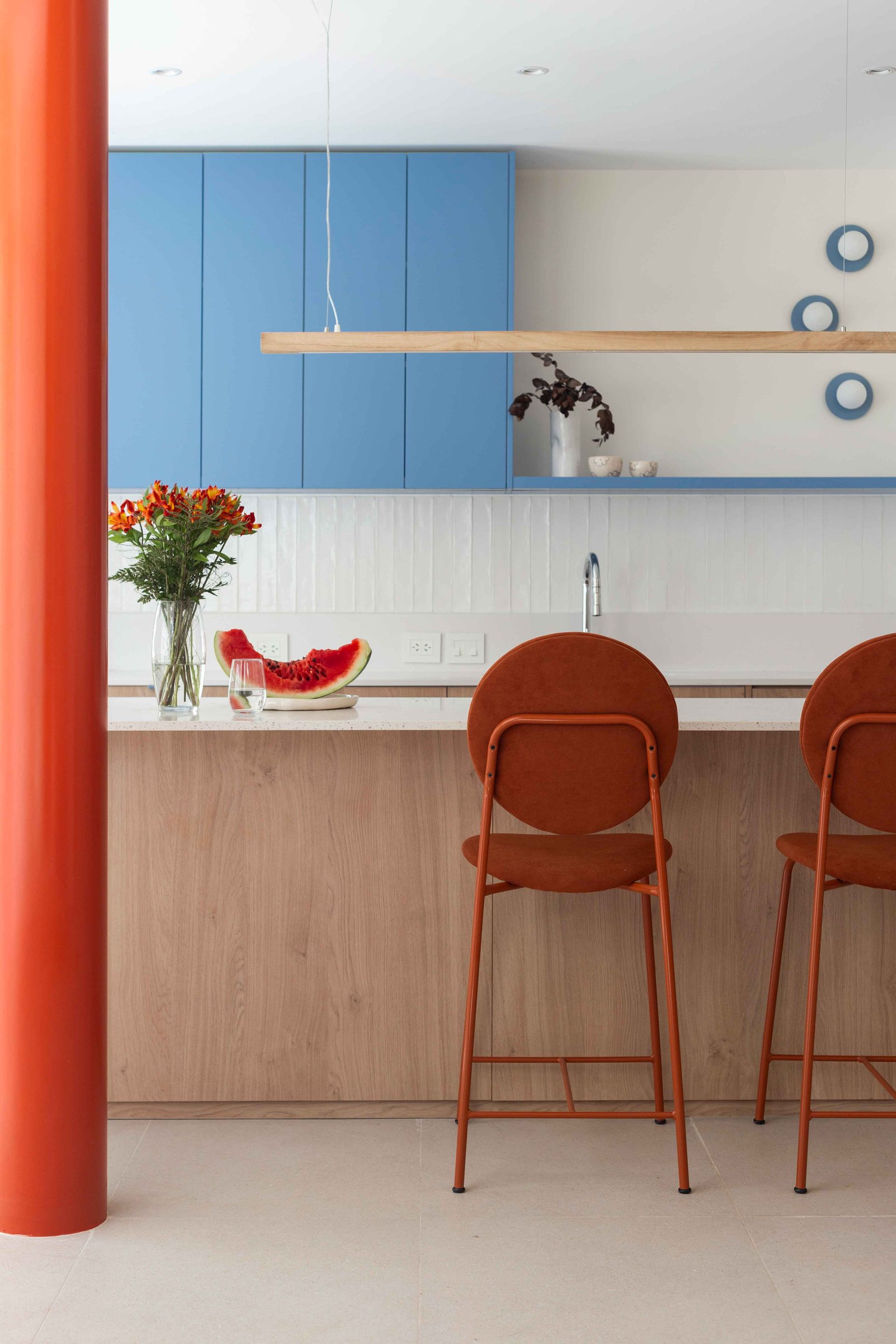 Cocina moderna con gabinetes azules y sillas naranjas — proyecto Grecia, por Bouré Studio, en Núñez