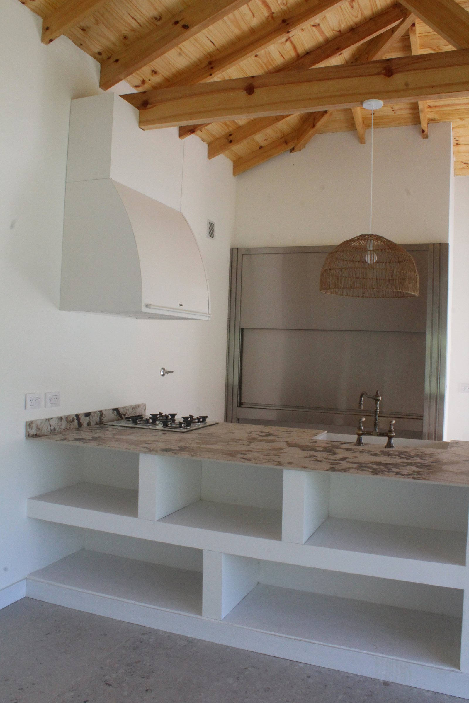 Cozinha rústica moderna com vigas de madeira e bancada de pedra — projeto CASA LA CASUALIDAD, por Estudio Grupo 32, em Pilar