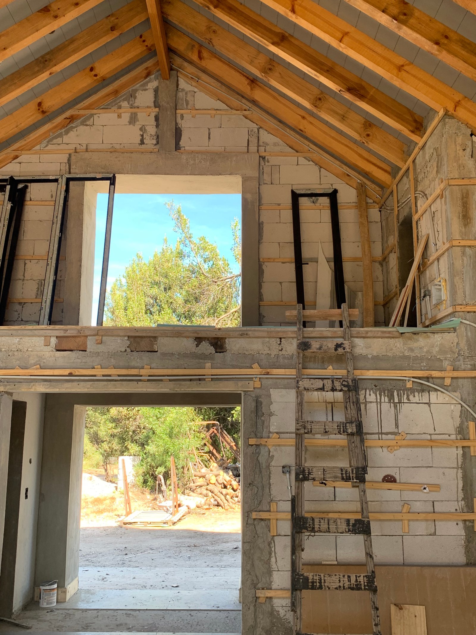 interior de obra con vigas de madera expuestas — proyecto Valle escondido, por Design & Living, en San Martín de los Andes
