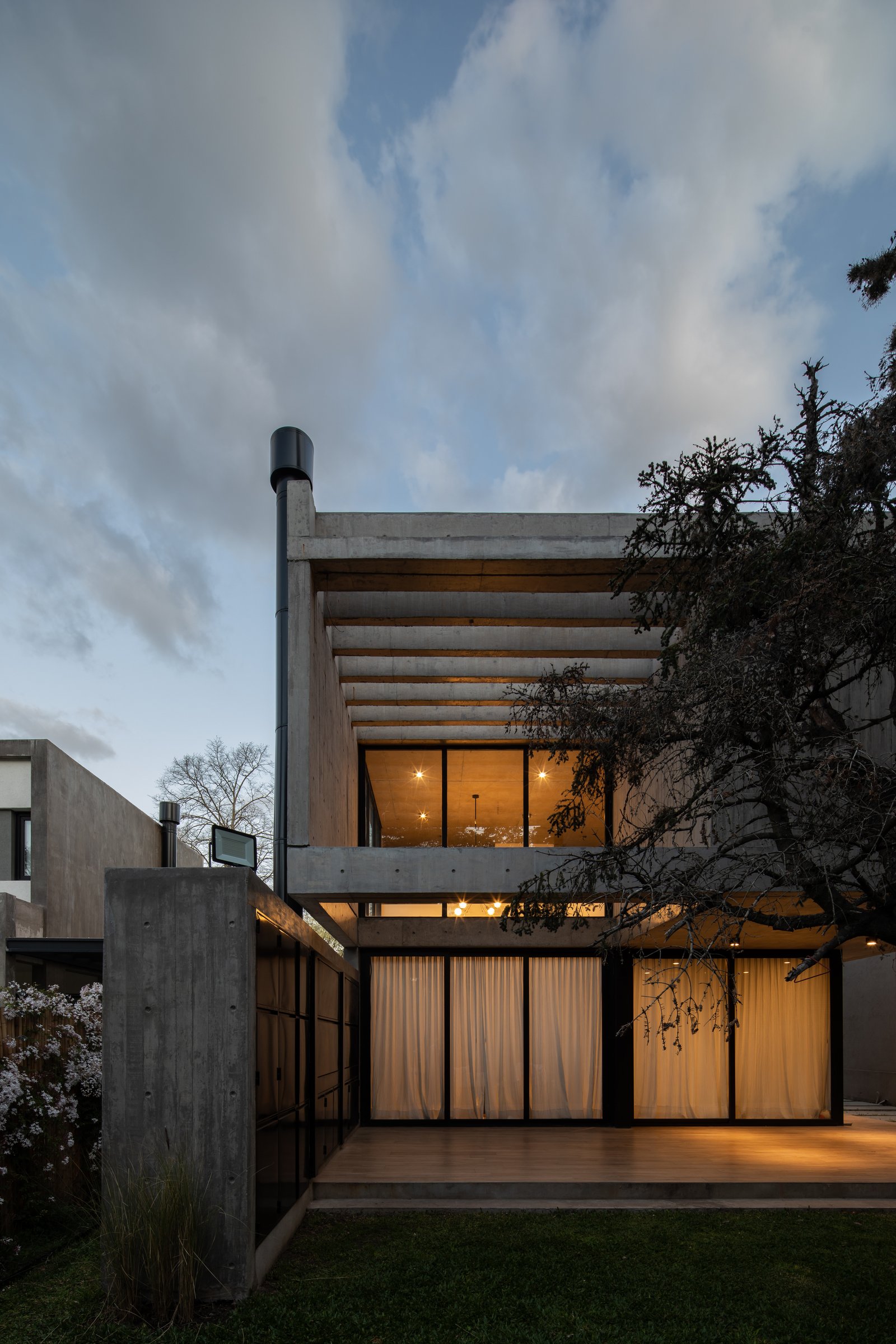 Fachada moderna brutalista com concreto aparente e grandes janelas — projeto Casa Emilia, por Grupo CRBN, em Parque Leloir