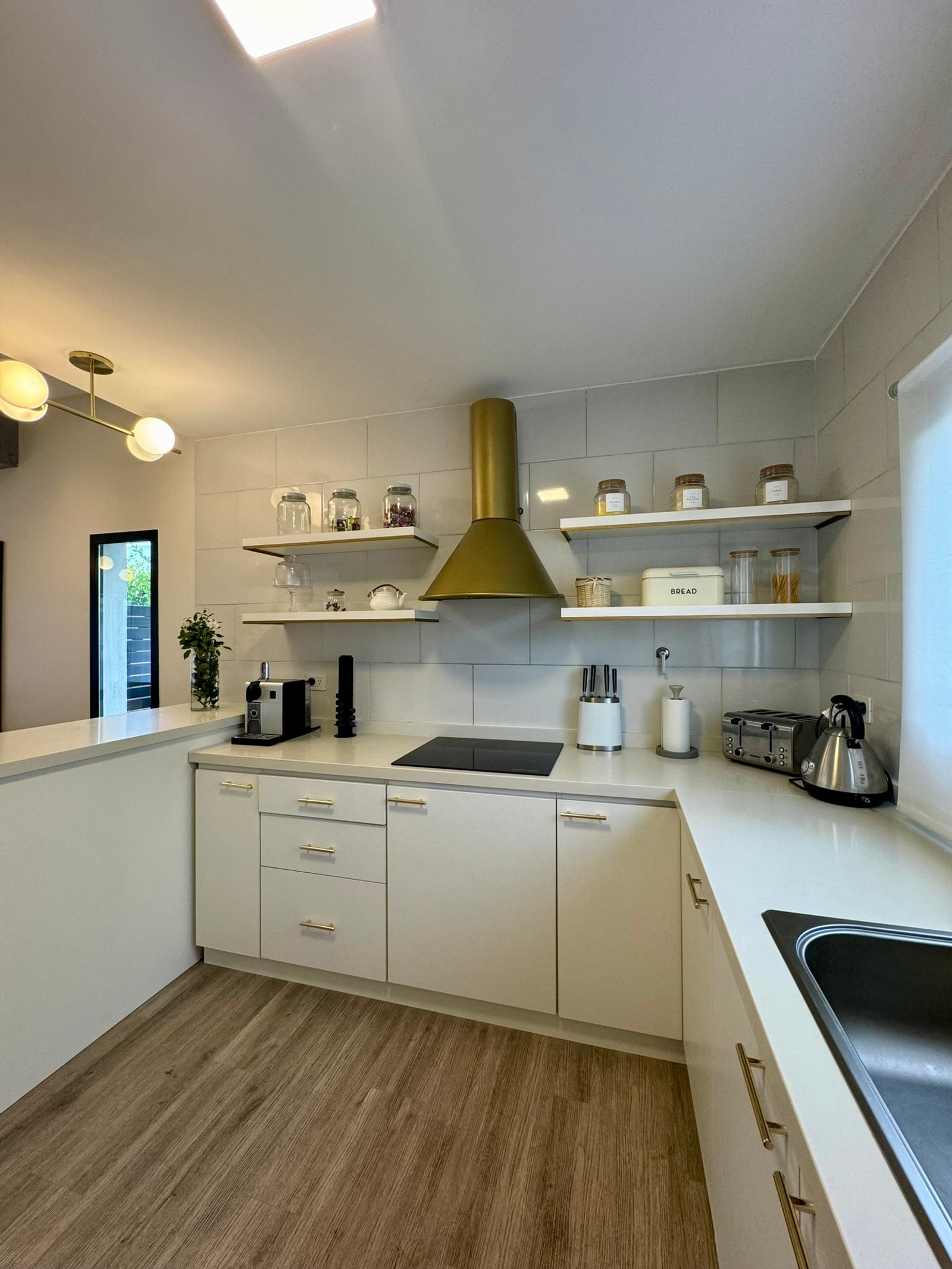 Cocina moderna estilo nórdico con campana dorada y acabados blancos — proyecto San Ramiro, por MDBK Arquitectura, en Pilar
