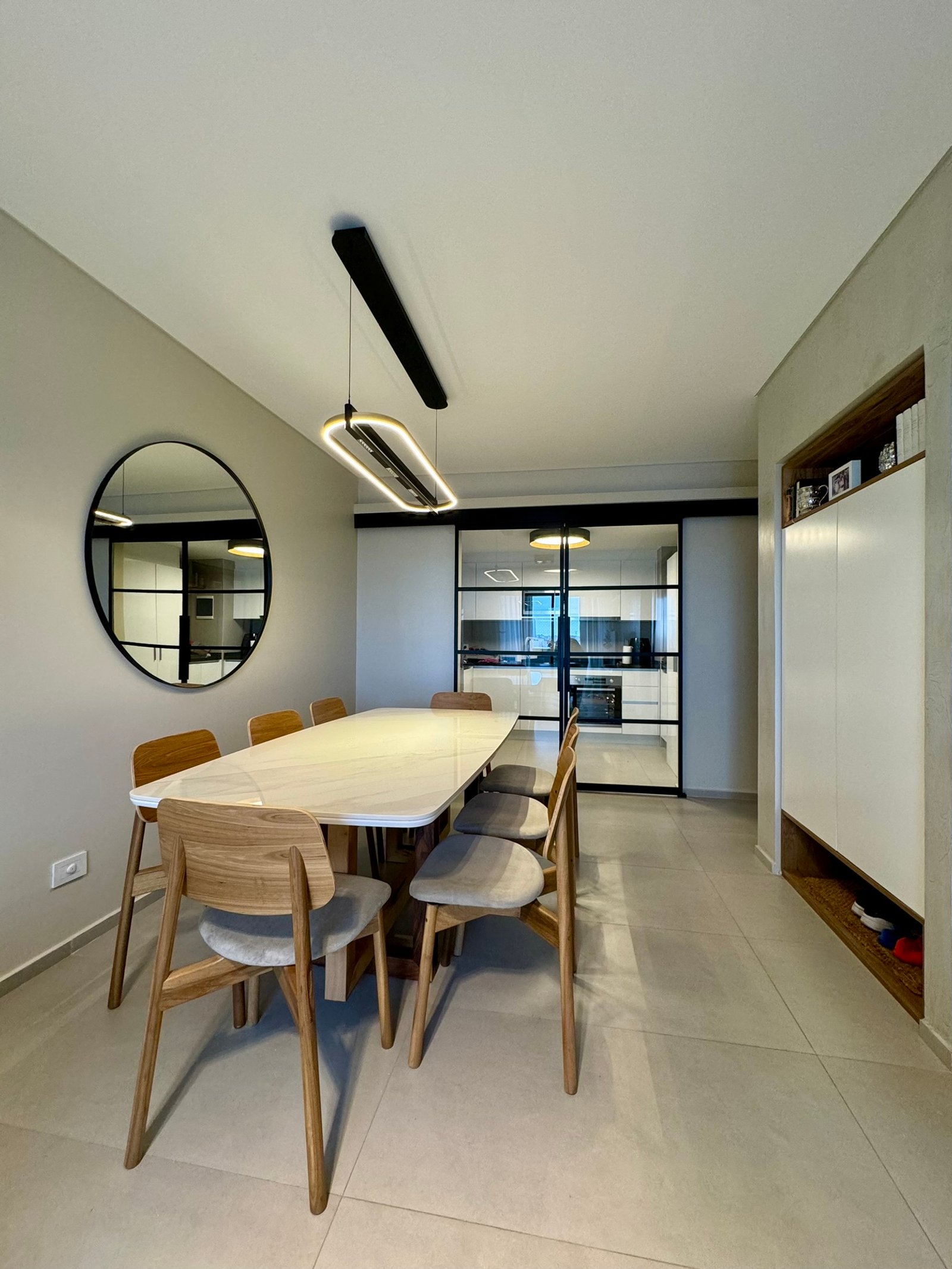 Sala de jantar moderna com mesa de mármore, cadeiras de madeira e lustre alongado — projeto Boyacá, por MDBK Arquitectura, em Caballito