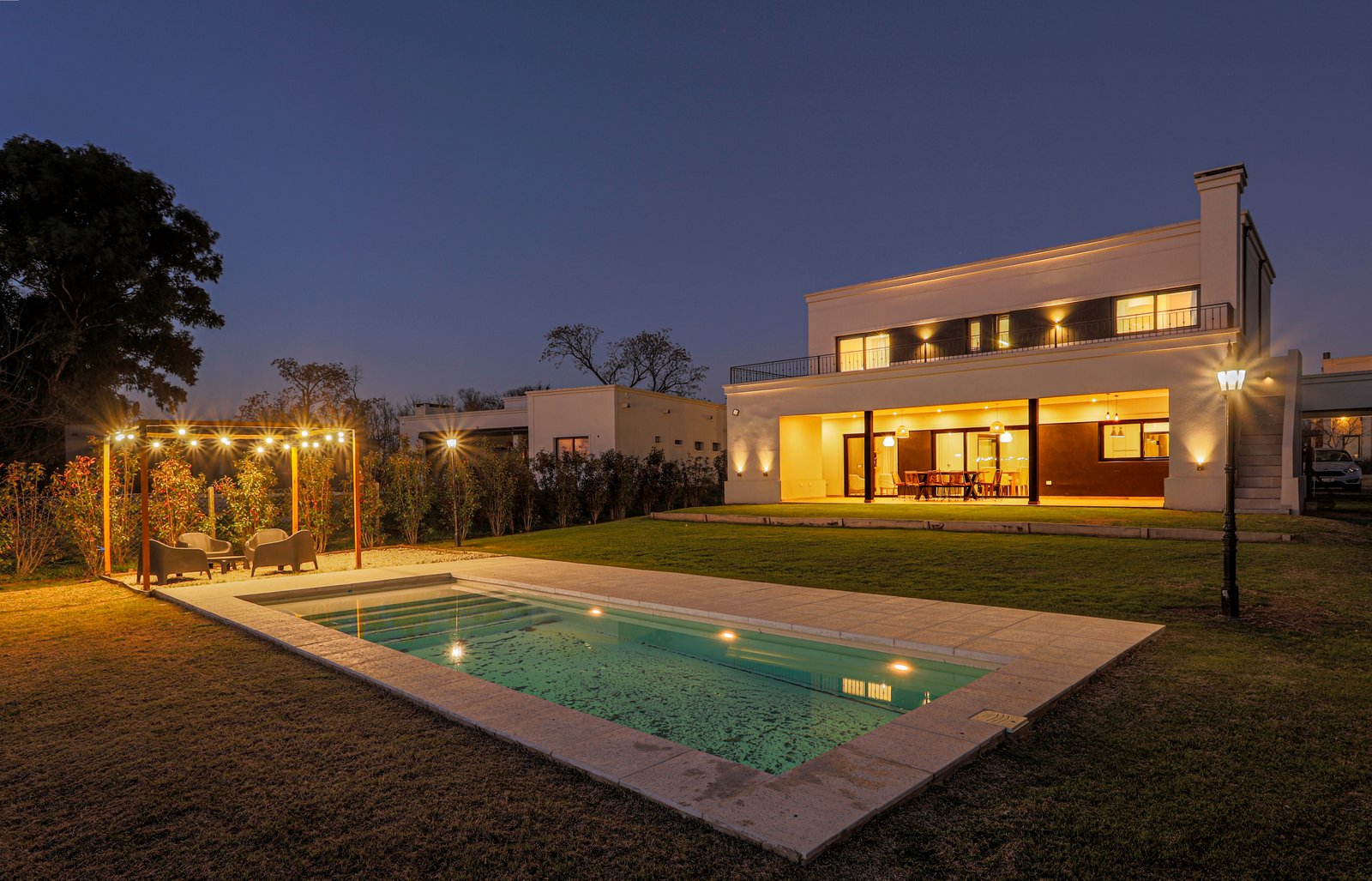 Fachada moderna con piscina iluminada de noche — proyecto SS45, por EZ architects, en Pilar