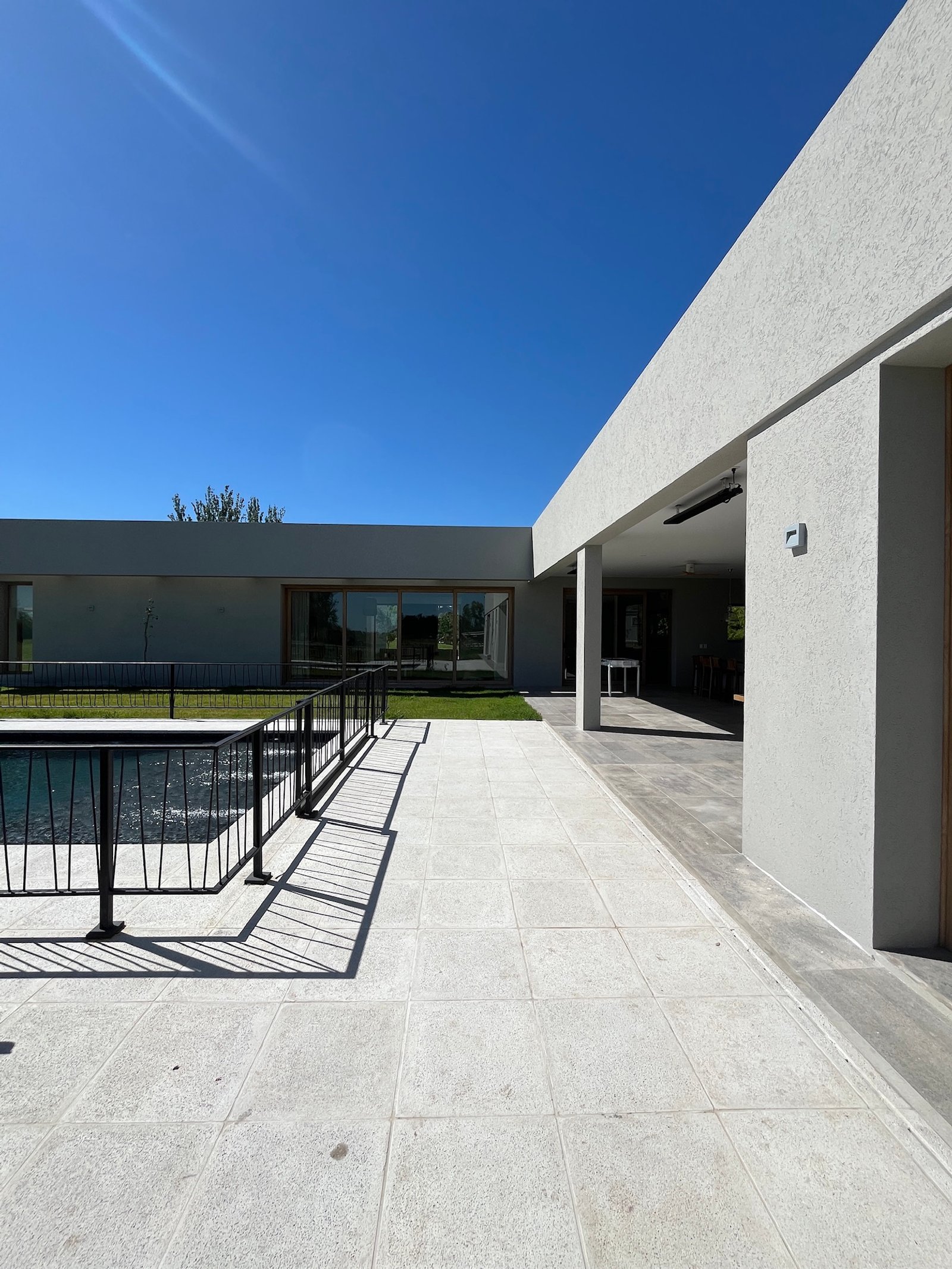 terraza moderna con piscina y rejas negras — proyecto La Colina, por Arcucci Arquitectura, en La Colina Villa de Campo