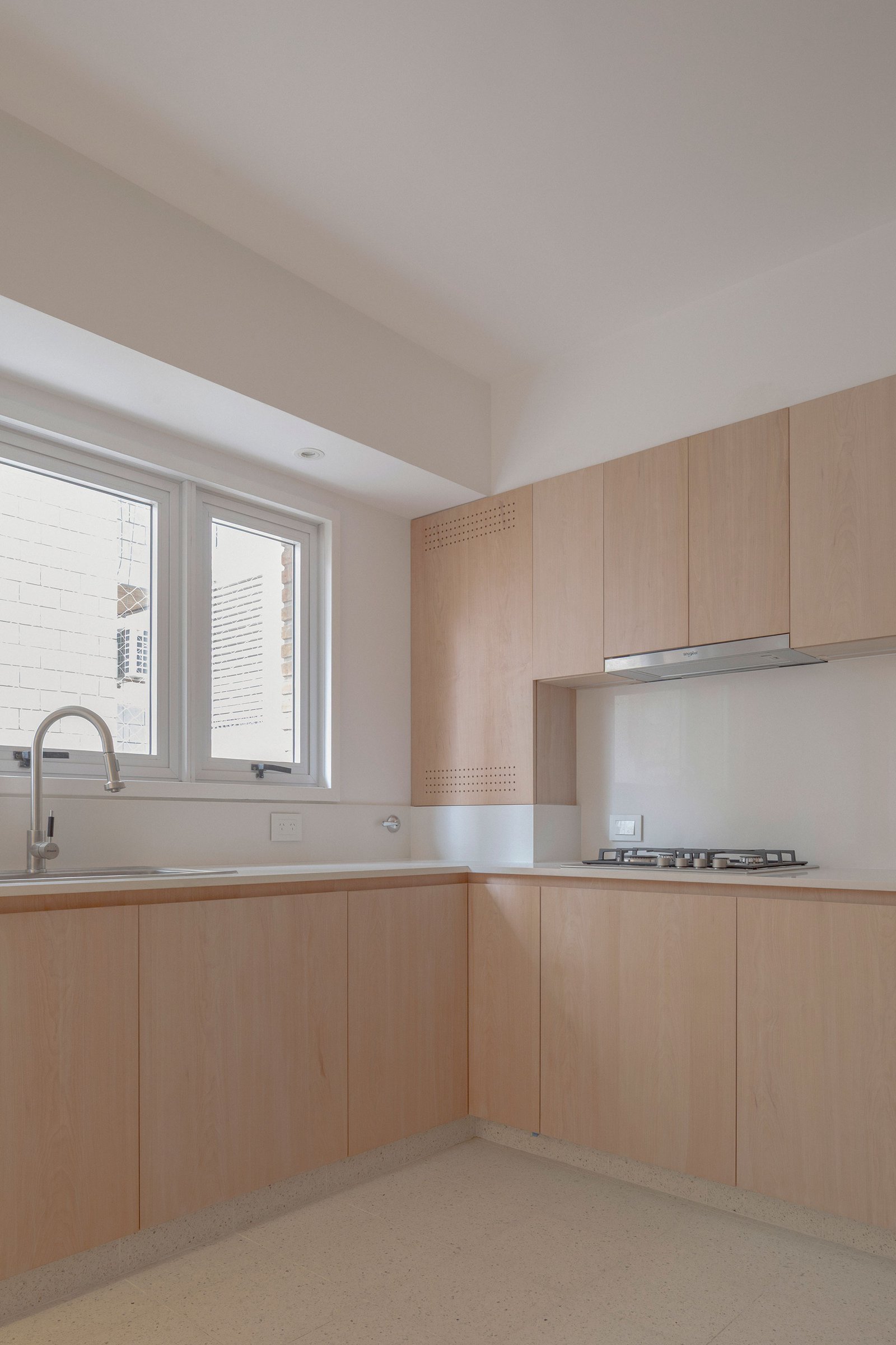Cocina moderna minimalista con muebles de madera clara y encimeras blancas — proyecto Reforma O'Higgins, por Estudio YME, en Belgrano