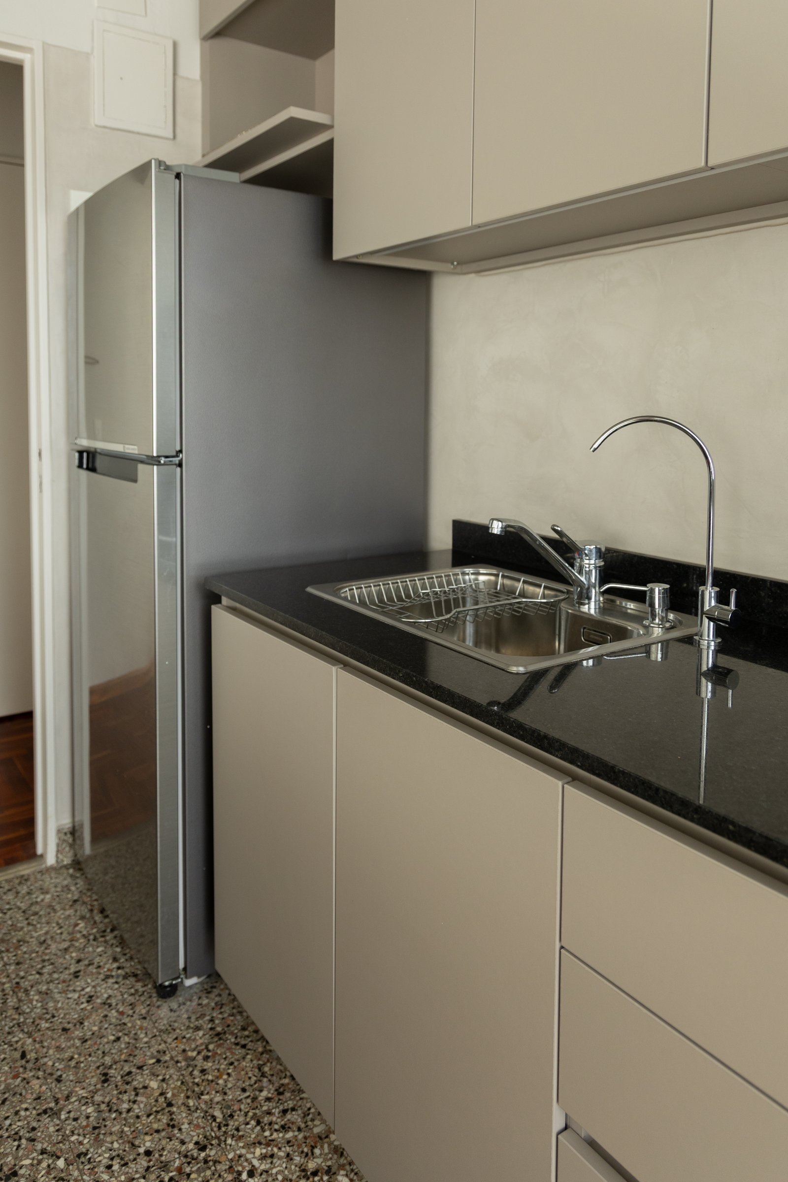 Cocina moderna con heladera de acero inoxidable, mesada de piedra negra y bacha doble — proyecto Arcos, por cromo., en Belgrano