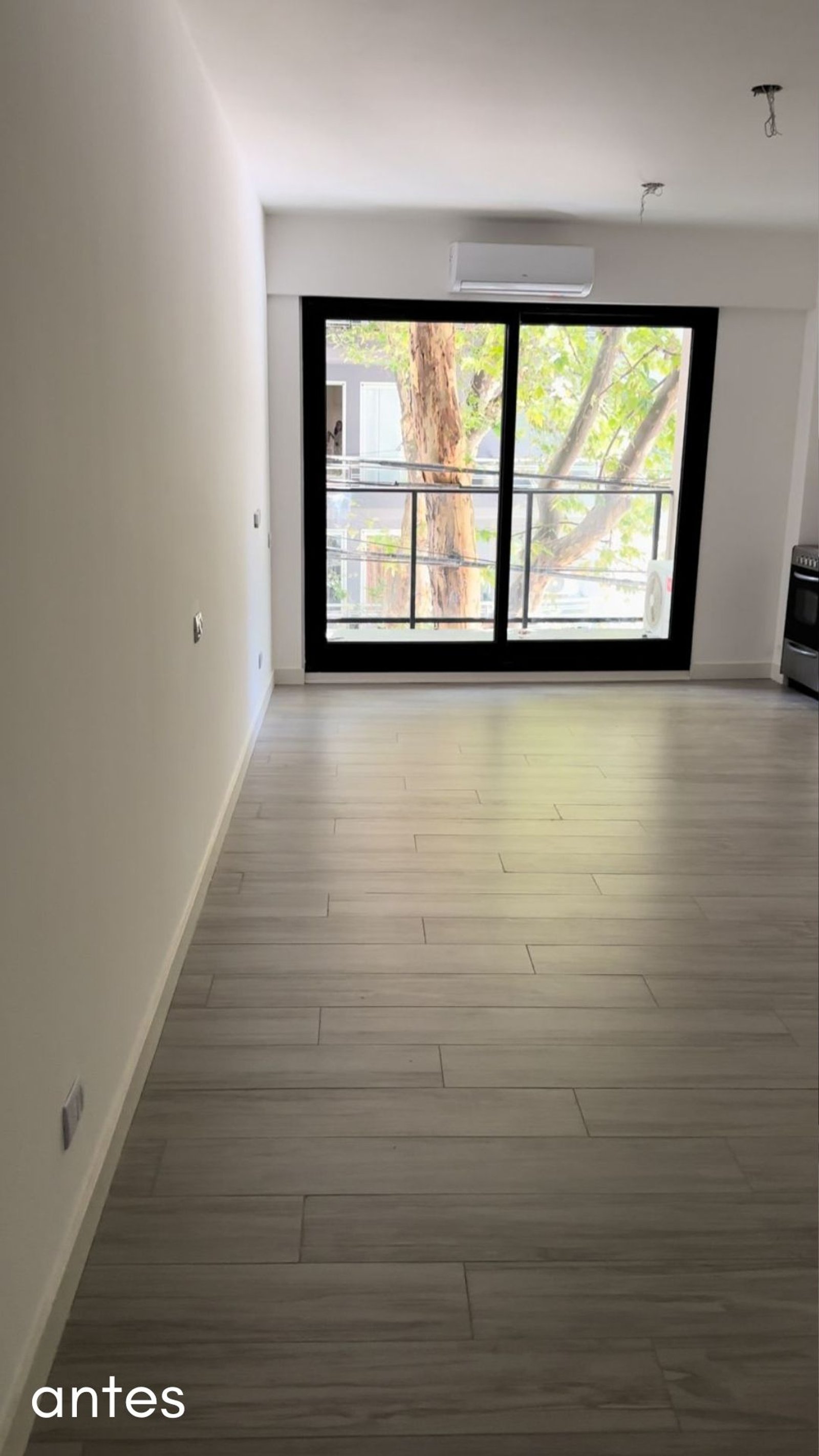 Sala de estar com janela grande e piso de cerâmica cinza — projeto Airbnb, por Estudio Hirsch, em Buenos Aires