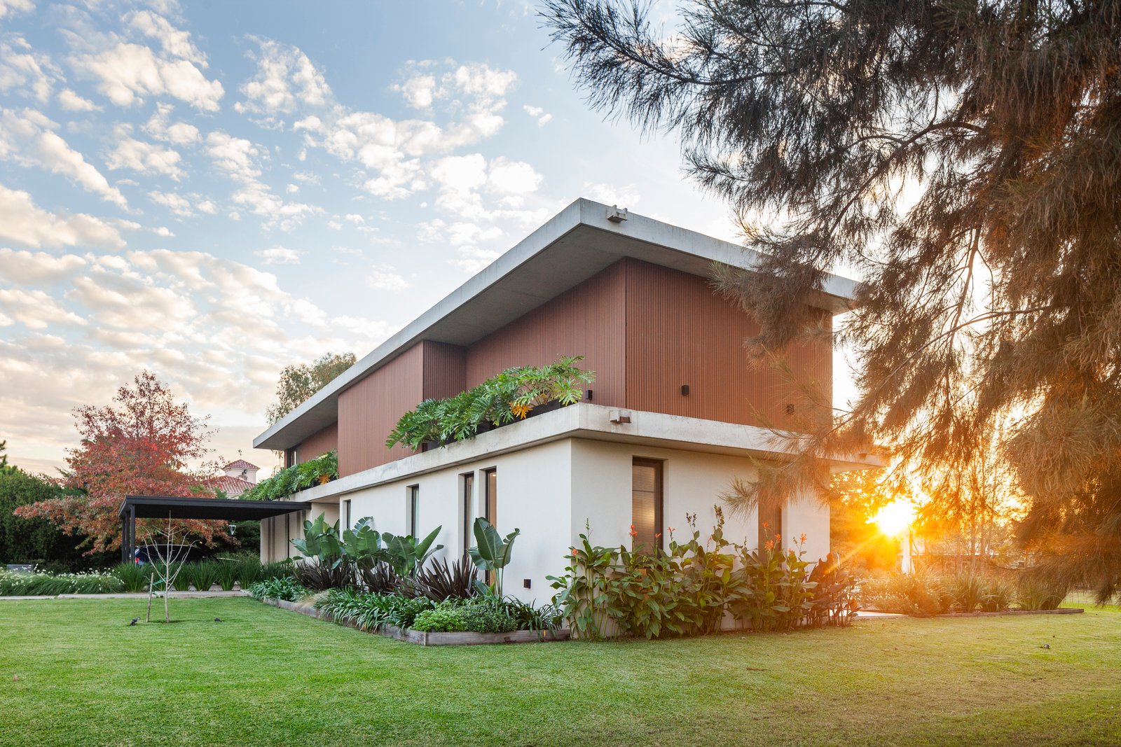 Fachada moderna con revestimiento de madera y grandes ventanales — proyecto CASA HS143, por A'PRIMA - Arquitectura Sustentable, en km 7.5 Ruta 25