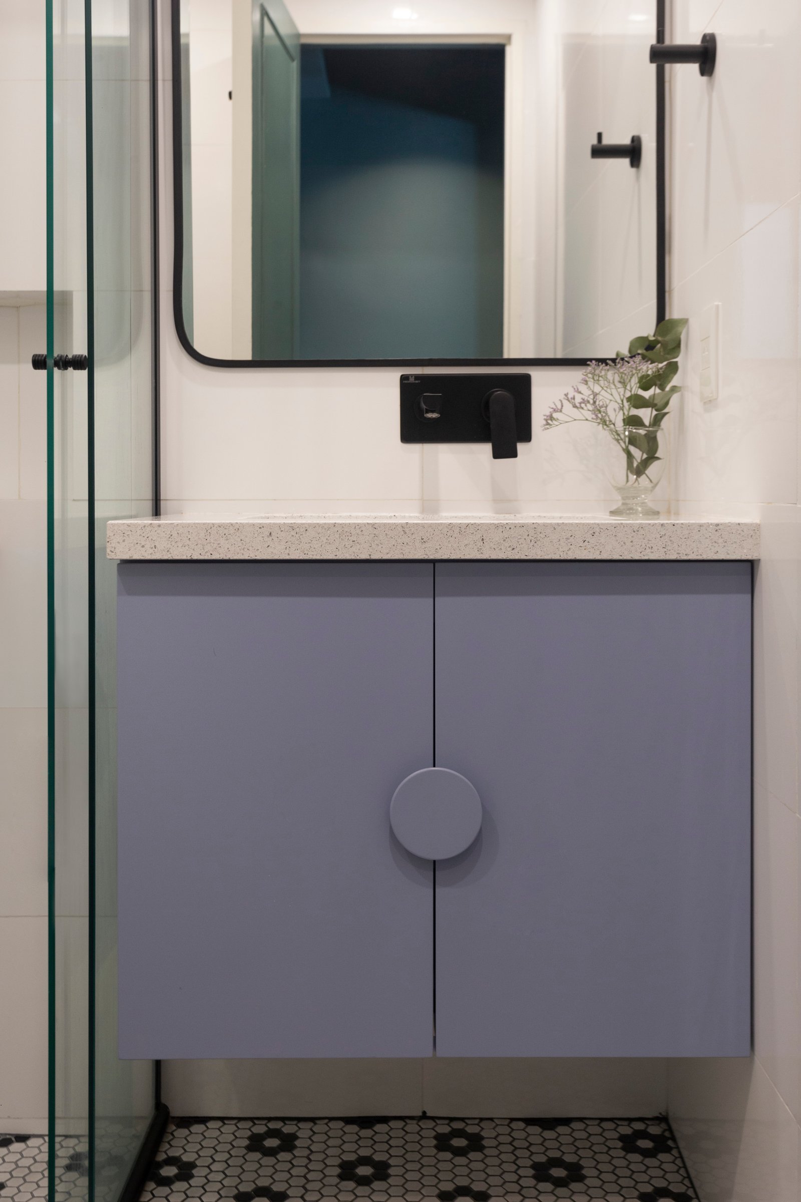 Baño moderno con mueble azul, espejo redondeado y grifería negra — proyecto Paraná, por JT ARQUITECTURA, en Buenos Aires