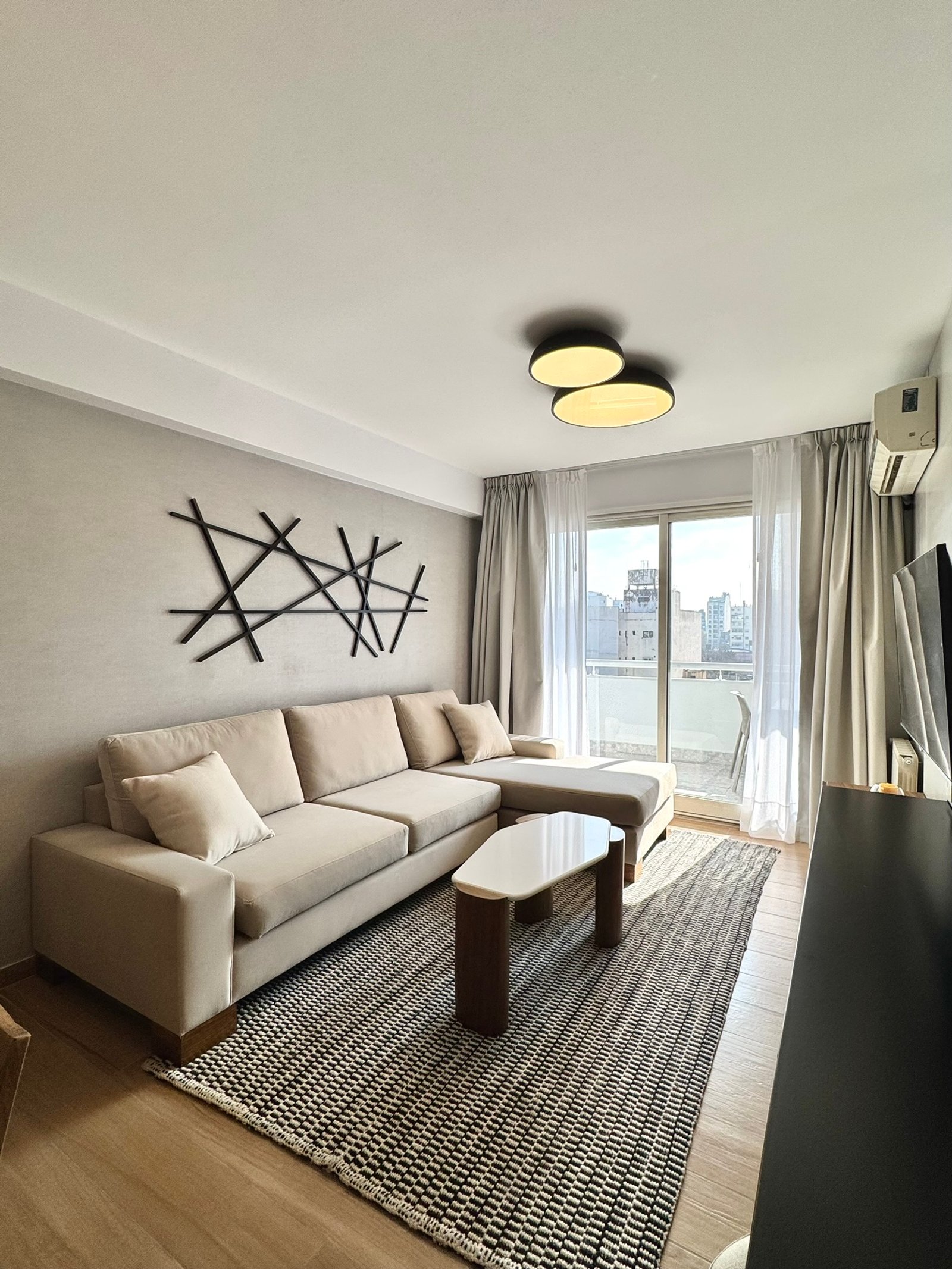 Living moderno con sofá seccional beige y arte geométrico — proyecto Arengreen, por MDBK Arquitectura, en Caballito