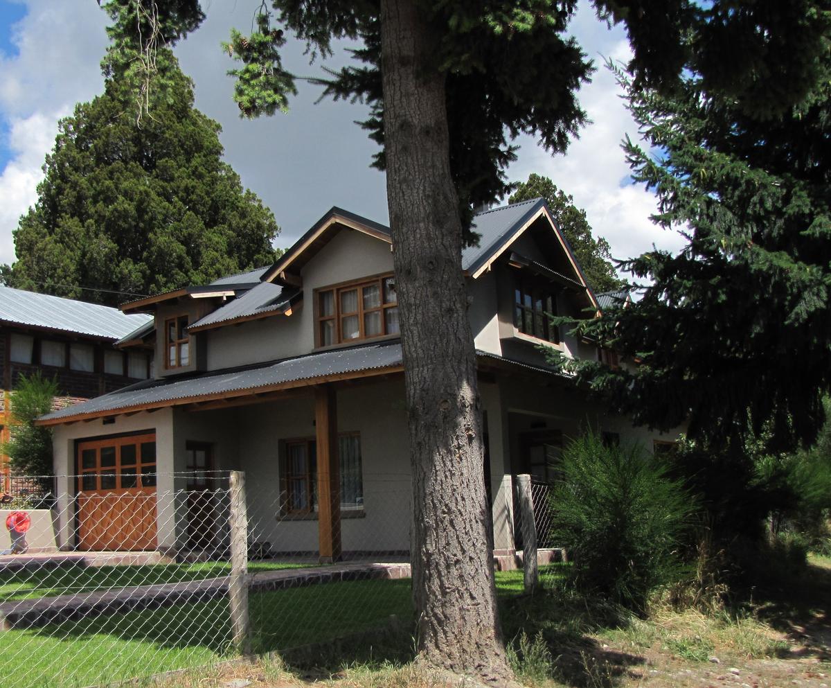 Casa rústica de campo com telhas e árvores — projeto Vivienda Familiar, por ESTUDIO ARQ.GABRIEL ARIAS, em San Carlos de Bariloche