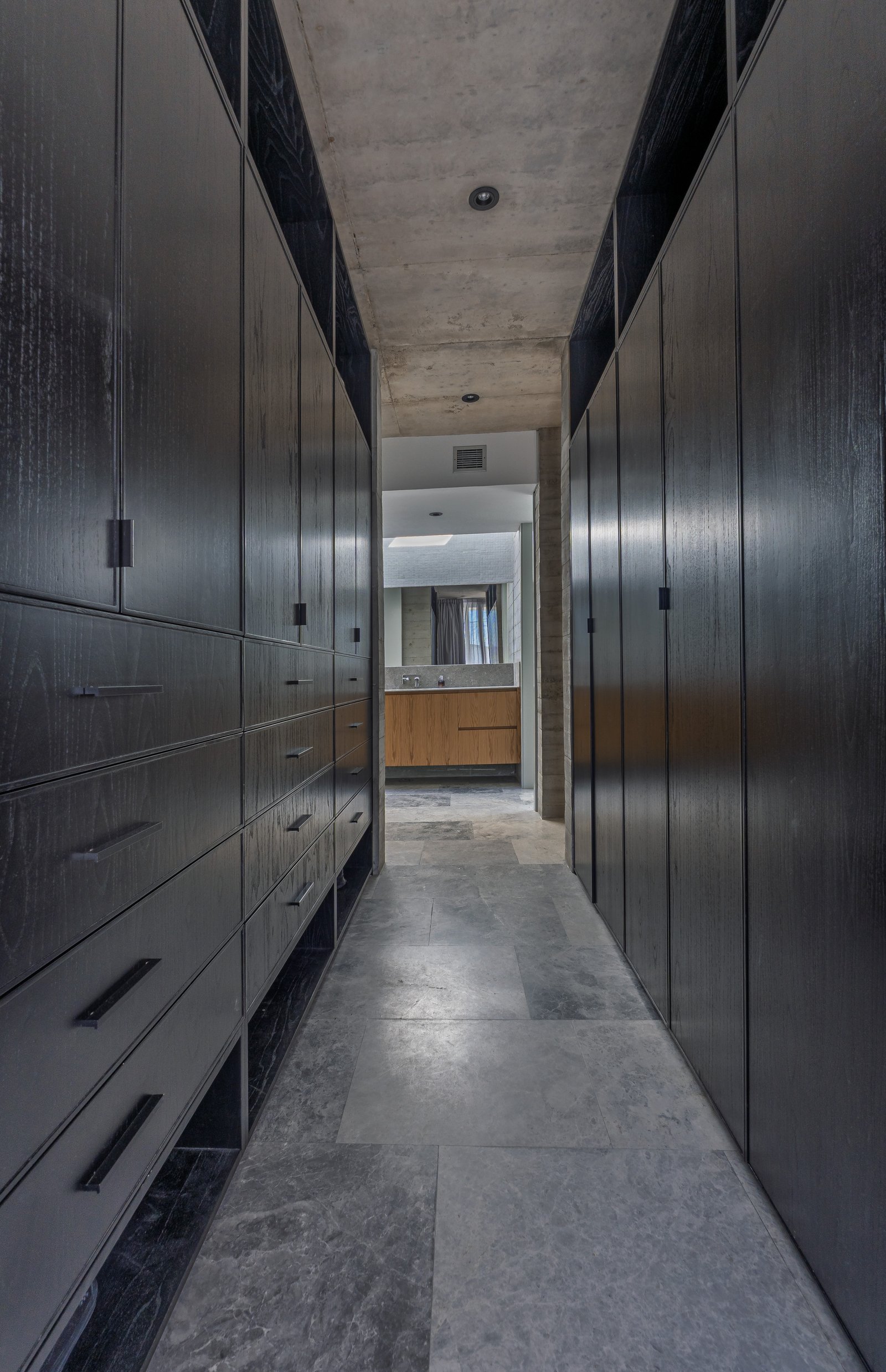 Pasillo moderno con armarios altos de madera oscura y techo de hormigón — proyecto La Martona - Estudio Barcelona, por ABEJA CONCEPT, en Cañuelas