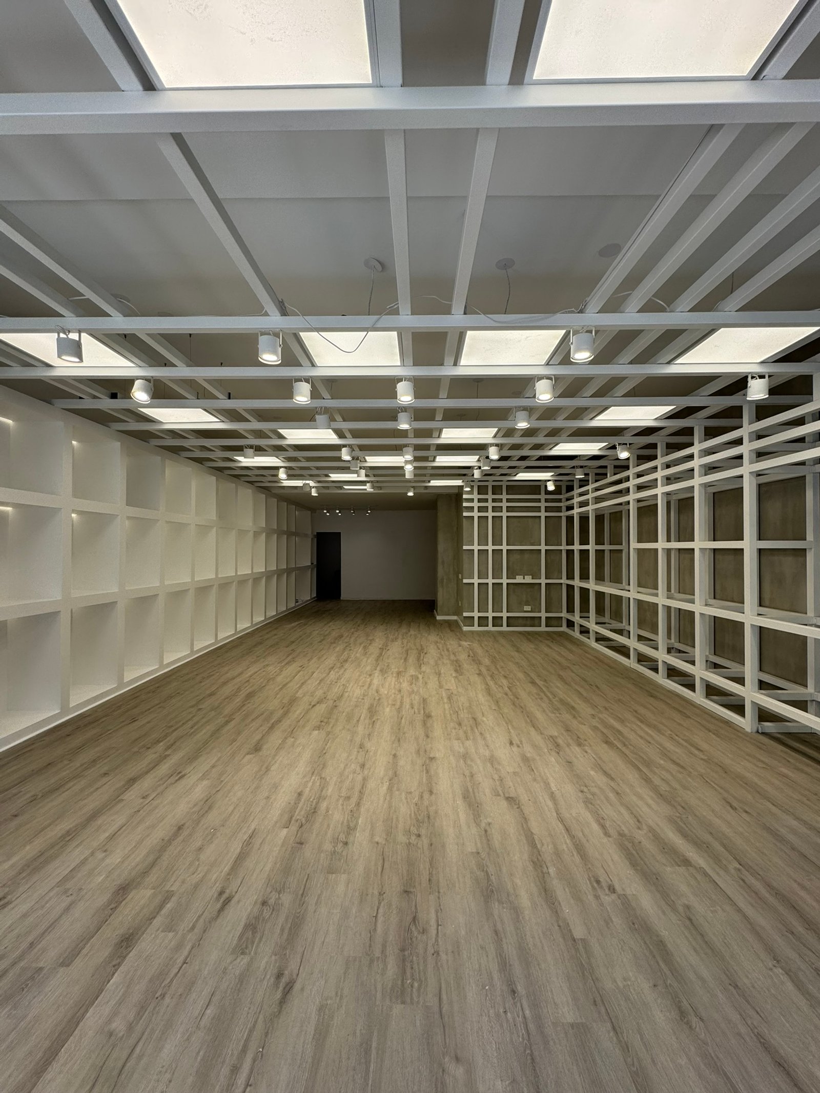 Espacio comercial minimalista con suelo de madera y estanterías blancas — proyecto Leonardo Marroquinería, por MDBK Arquitectura, en Balvanera