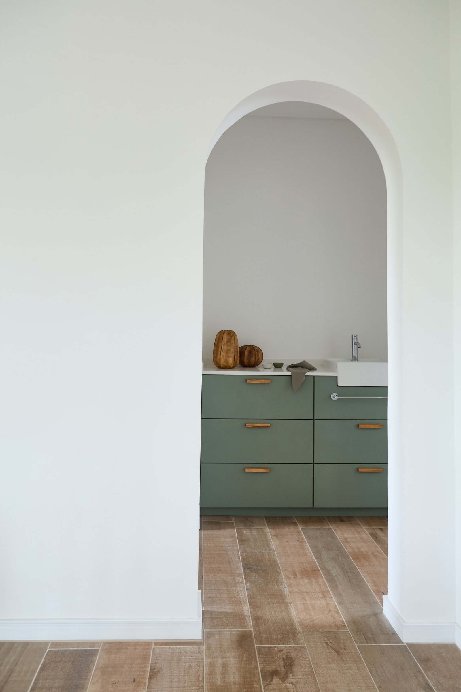 Baño moderno con arco, gabinetes verdes y piso de madera — proyecto Baños, por CASA1-TROMEN, en Bella Vista