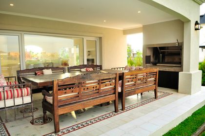 Quincho moderno con mesa de madera, asador y jardín verde al fondo — proyecto Estilo Clásico, por Ciba Arquitectura
