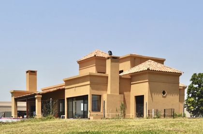Fachada moderna con tejado de tejas de terracota y pérgolas — proyecto San Marcos, por Marconi Silva Arquitectos, en Benavidez
