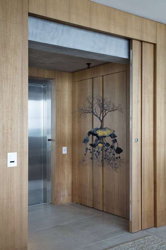 Pasillo moderno con ascensor y puerta de madera, instalación artística árbol — proyecto PL House, por Studio Ro-ca