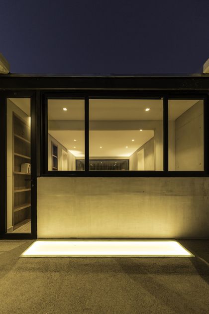 Terraza moderna con piso iluminado y ventanal negro al atardecer — proyecto CASA ARFE, por Valeria Valdivieso Arquitecta, en Ciudad de Mendoza