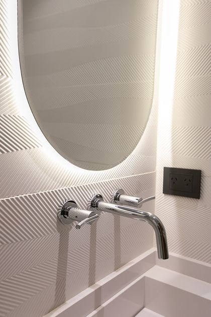 Baño minimalista blanco con espejo oval iluminado y grifería cromada — proyecto Casa Oroño, por Estudio Plats, en Buenos Aires