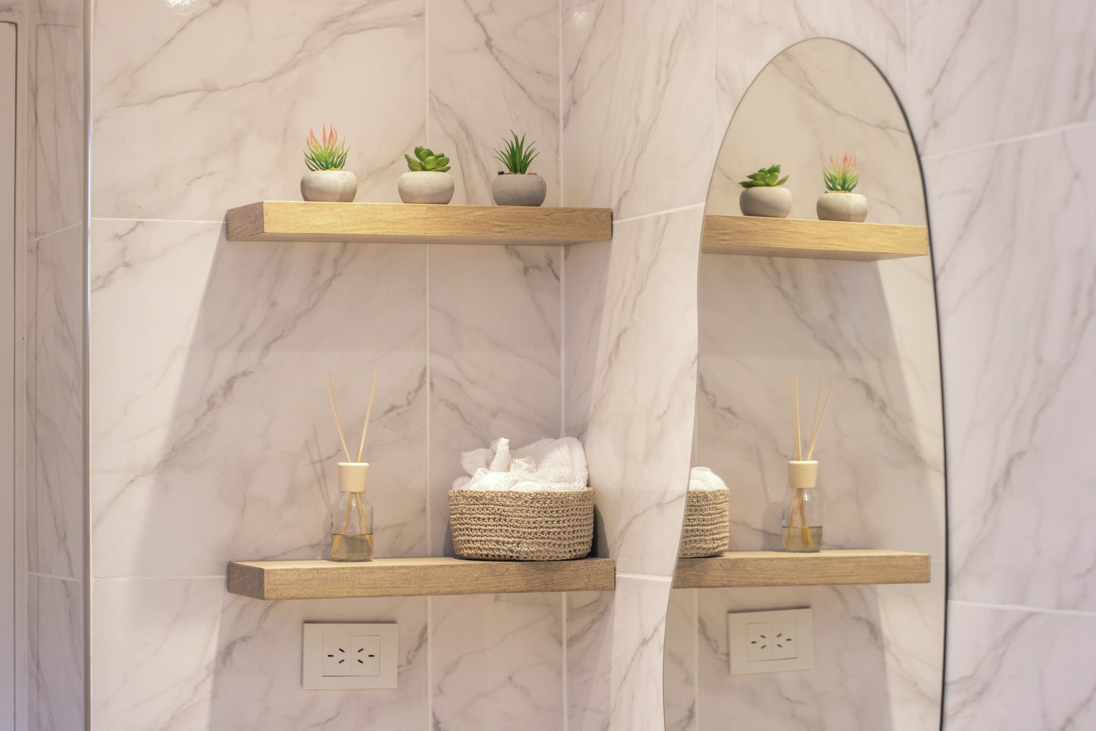 Baño moderno con estantes de madera y espejo ovalado — proyecto Estudio MDBK, por MDBK Arquitectura, en Almagro