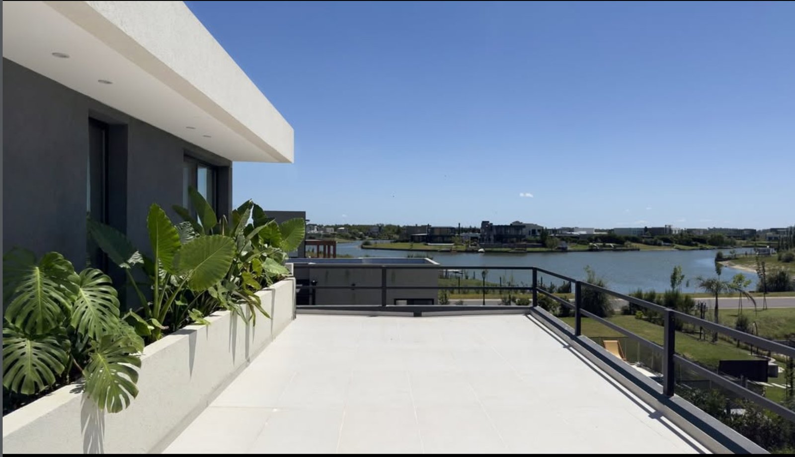 Terraza moderna con vista al agua y vegetación exuberante — proyecto Casa SS, por MMCZ STUDIO, en Pilar