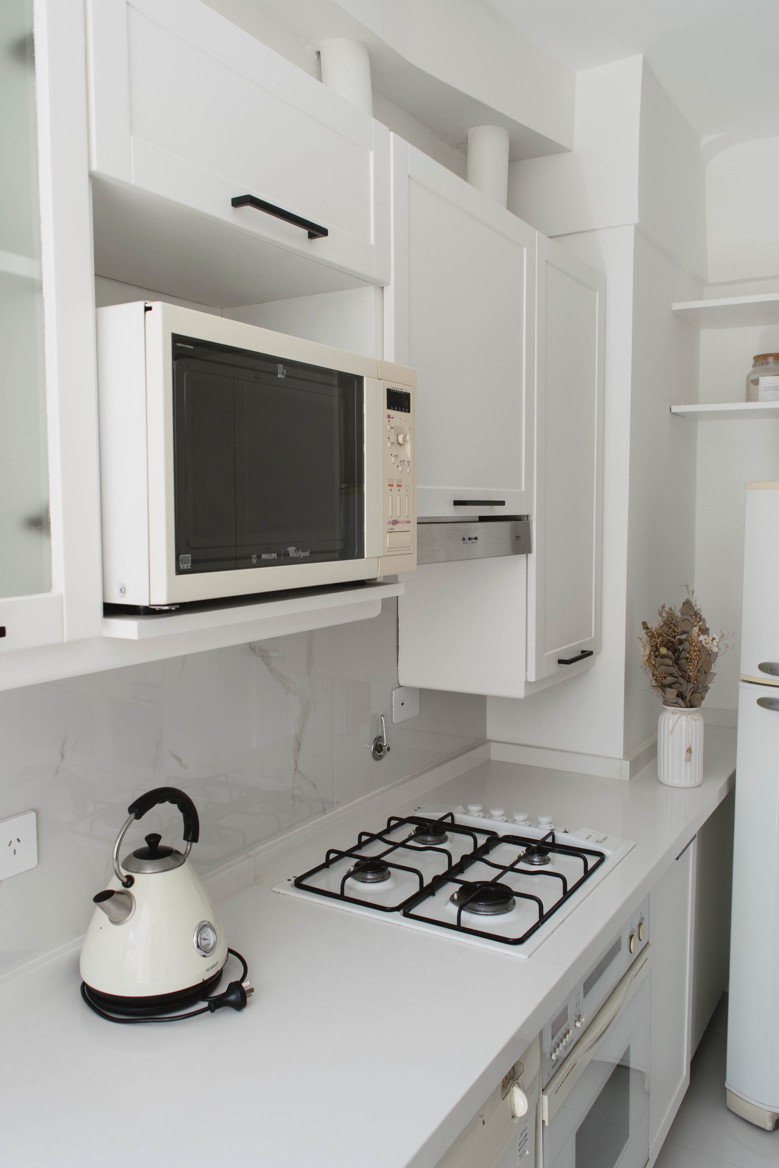 Cocina moderna blanca con heladera eléctrica y horno a gas — proyecto Goyena, por Martina Kleinert, en Caballito