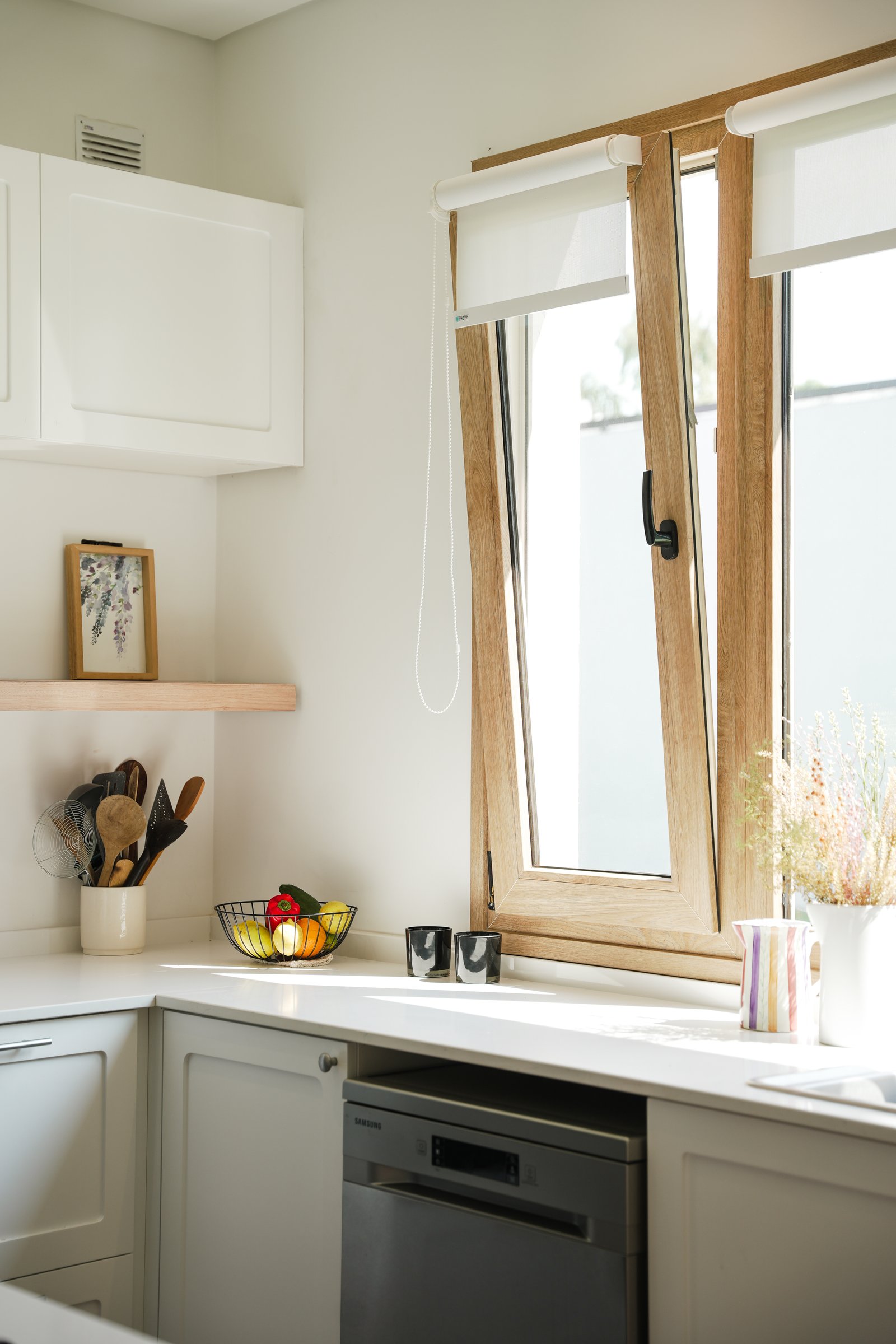 Cozinha moderna com armários brancos, bancadas de mármore e janela grande de madeira — projeto Cocina, por CASA1-TROMEN, em Bella Vista