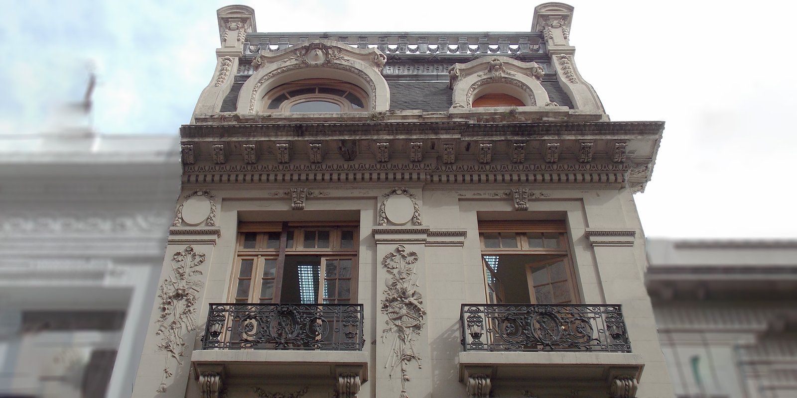 Fachada de edificio clásico con detalles de estuco y balcones ornamentados — proyecto Petit Hotel Montevideo, por M. Victoria Menendez | Arq. Esp. en Patrimonio, en Montevideo 696