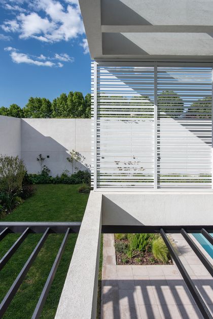 Jardín moderno con pérgola, paredes de hormigón y césped — proyecto CASA SD28, por GMARQ, en Buenos Aires