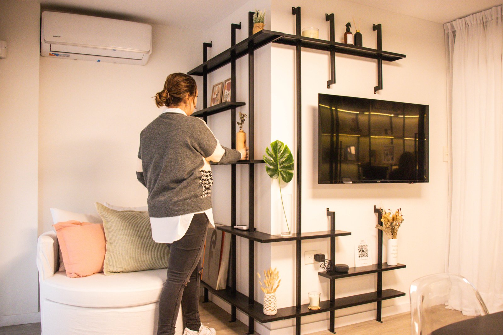 Living moderno con estantería negra alta y sofá curvo beige — proyecto Estudio MDBK, por MDBK Arquitectura, en Almagro