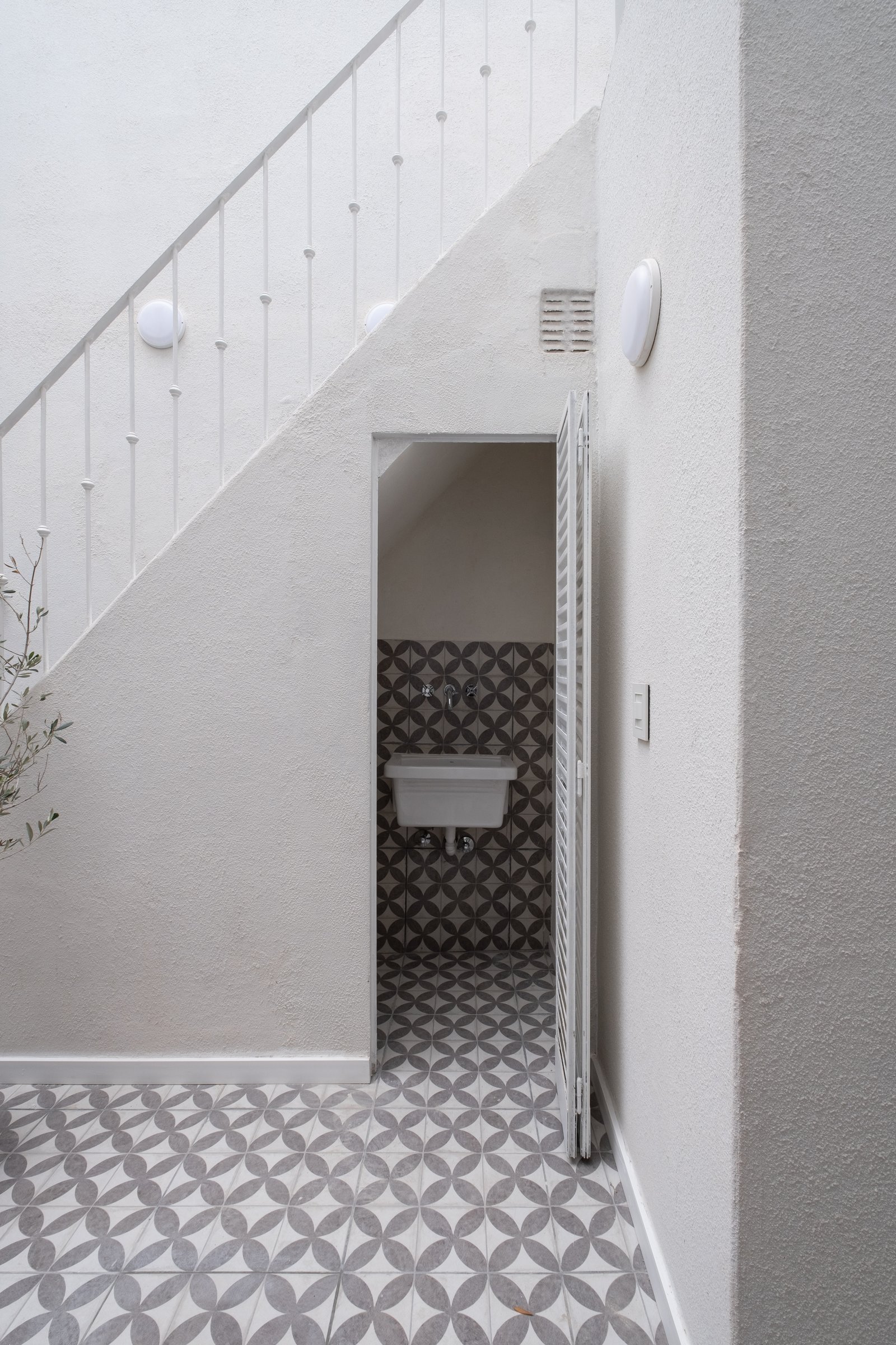 Corredor moderno com escada, piso geométrico e pia de parede — projeto Casa Patio, por Herrera Ungaro, em San Cristóbal
