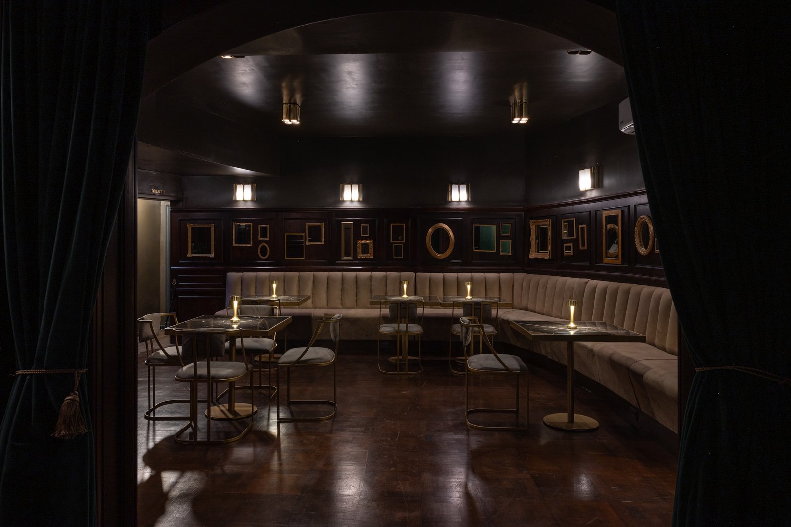 Interior de bar clássico com sofá curvo e iluminação quente — projeto PRESIDENTE BAR HIPODROMO, por AB ARQUITECTURA, em San Isidro