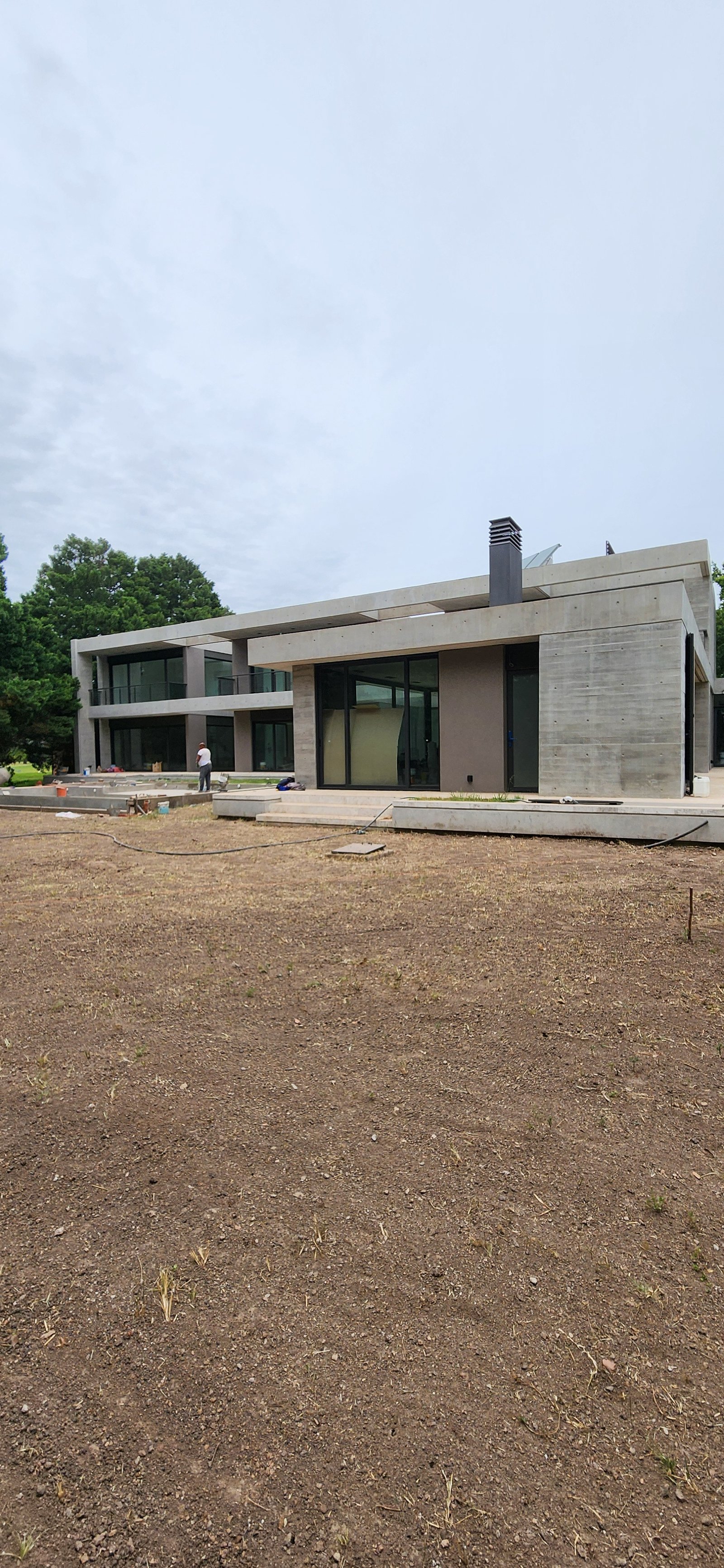 casa moderna en construccion fachada de hormigon visto — proyecto Casa CAD, por Estudio Rifahi, en Moreno