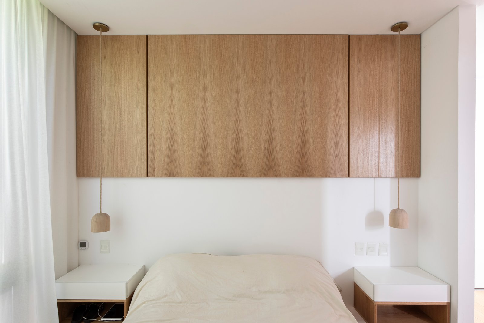 Dormitorio moderno con muebles de madera integrados y luz cálida — proyecto Casa MECHA, por Grupo CRBN, en B1712 Castelar