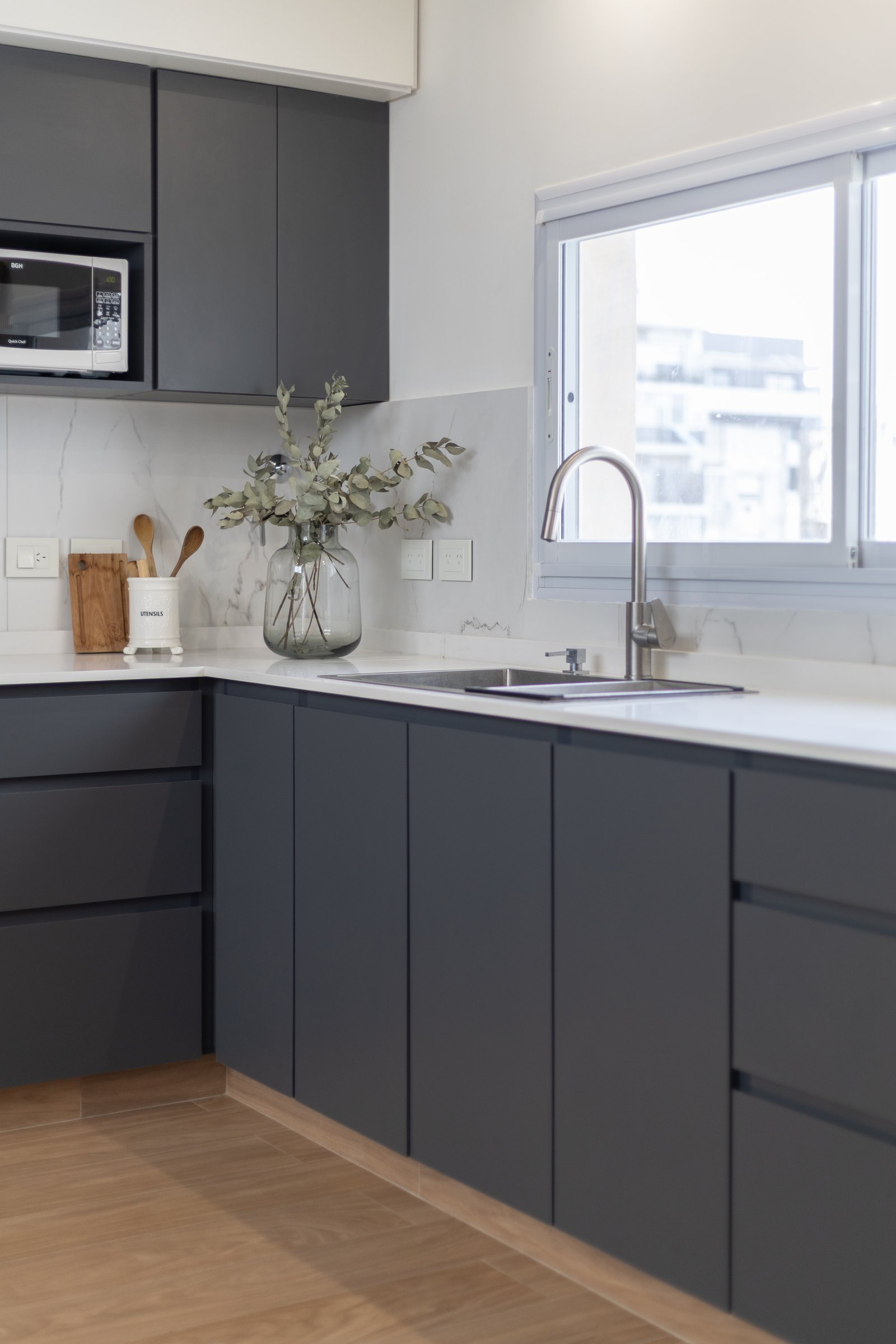 Cocina moderna con muebles grises oscuros, mesada de mármol y grifería arqueada — proyecto Boedo, por Martina Kleinert, en Boedo