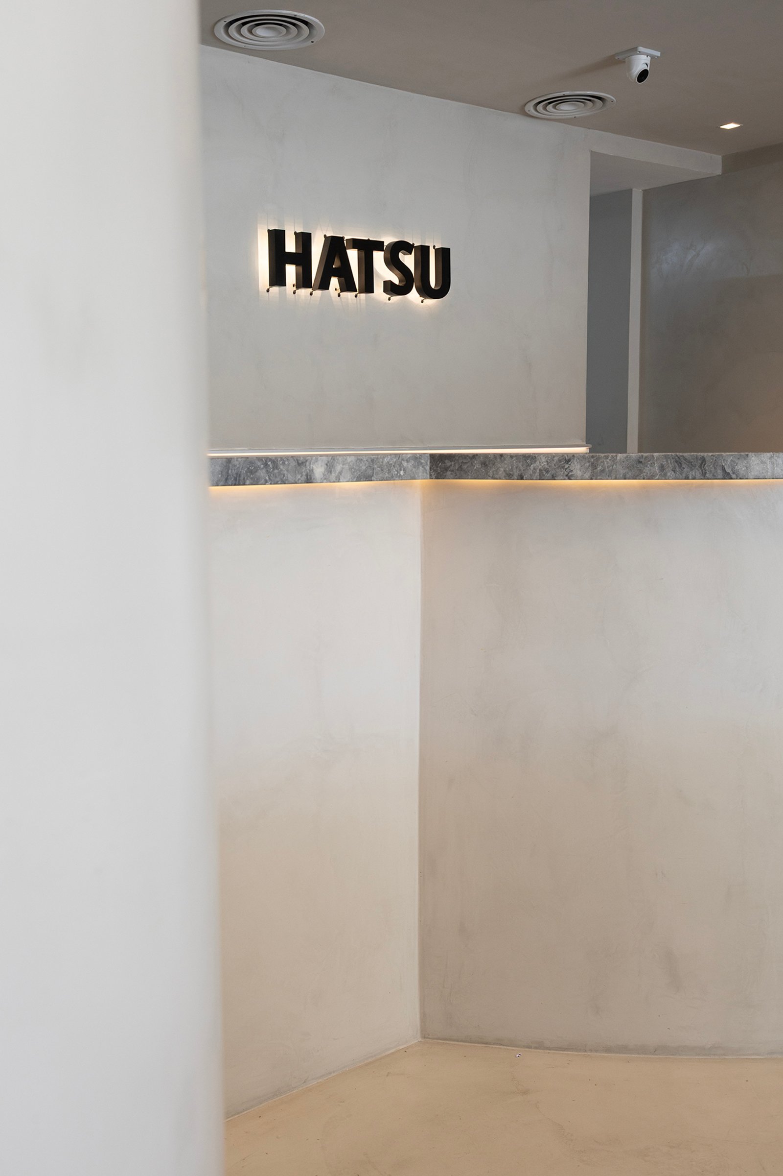Interior comercial minimalista com logo HATSU iluminado — projeto HATSU Núñez - MZV Arquitectura, por Gaby Alfonso, em Buenos Aires