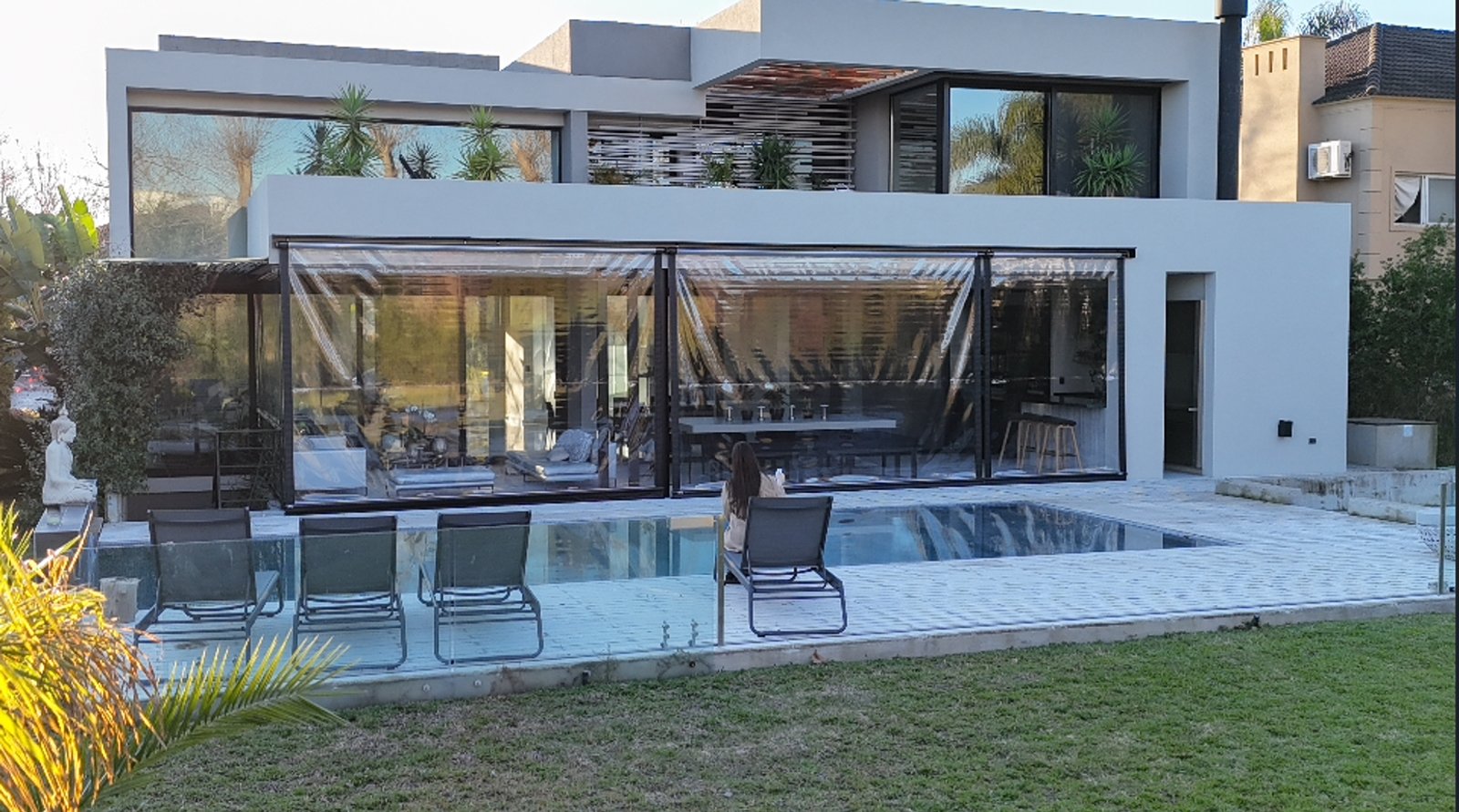 Casa moderna con piscina y cerramiento de vidrio retráctil — proyecto Toldos Verticales, por ToldosYa