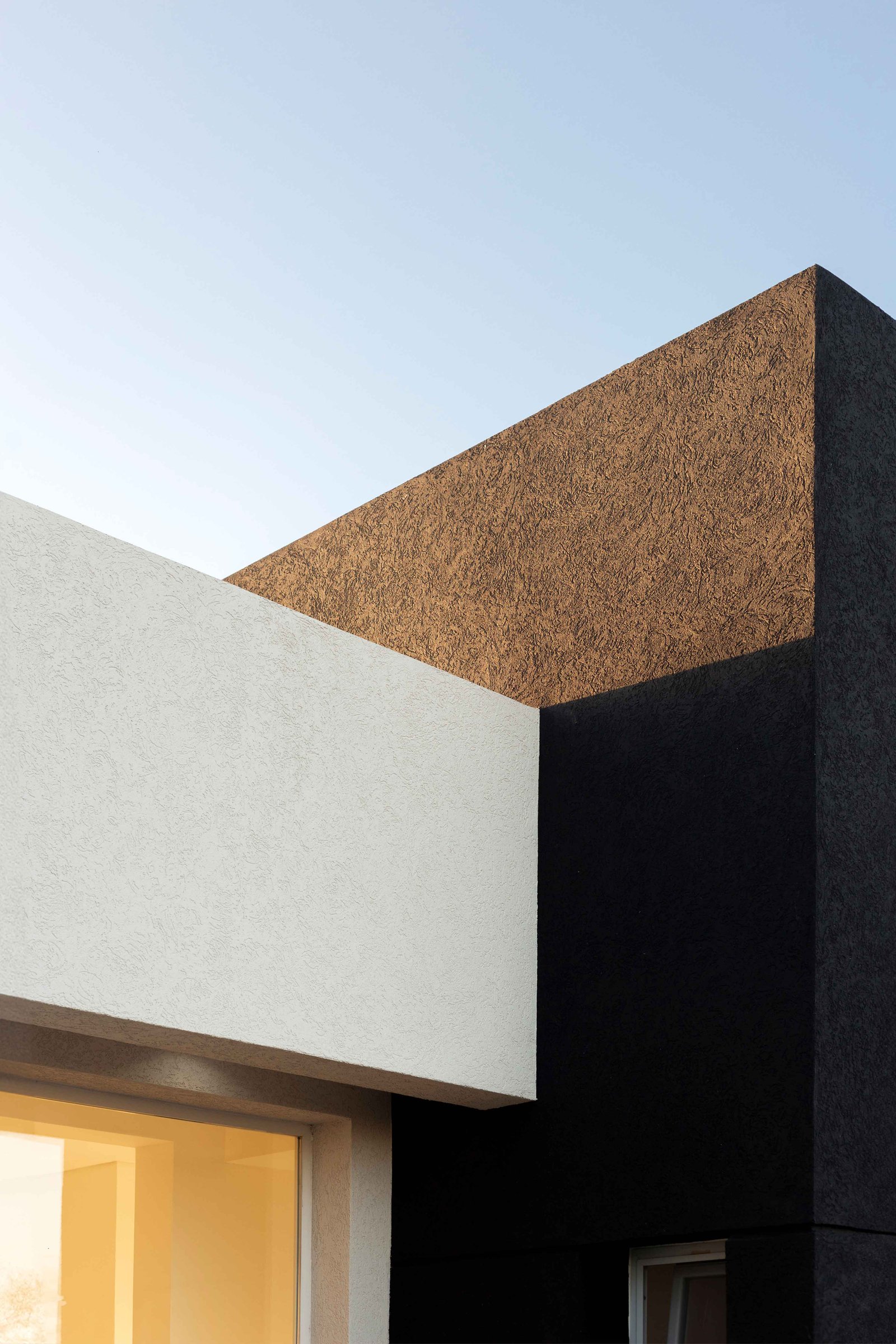 Fachada moderna con texturas contrastantes bajo cielo azul — proyecto San Simon I, por Estudio Stepa, en Ezeiza