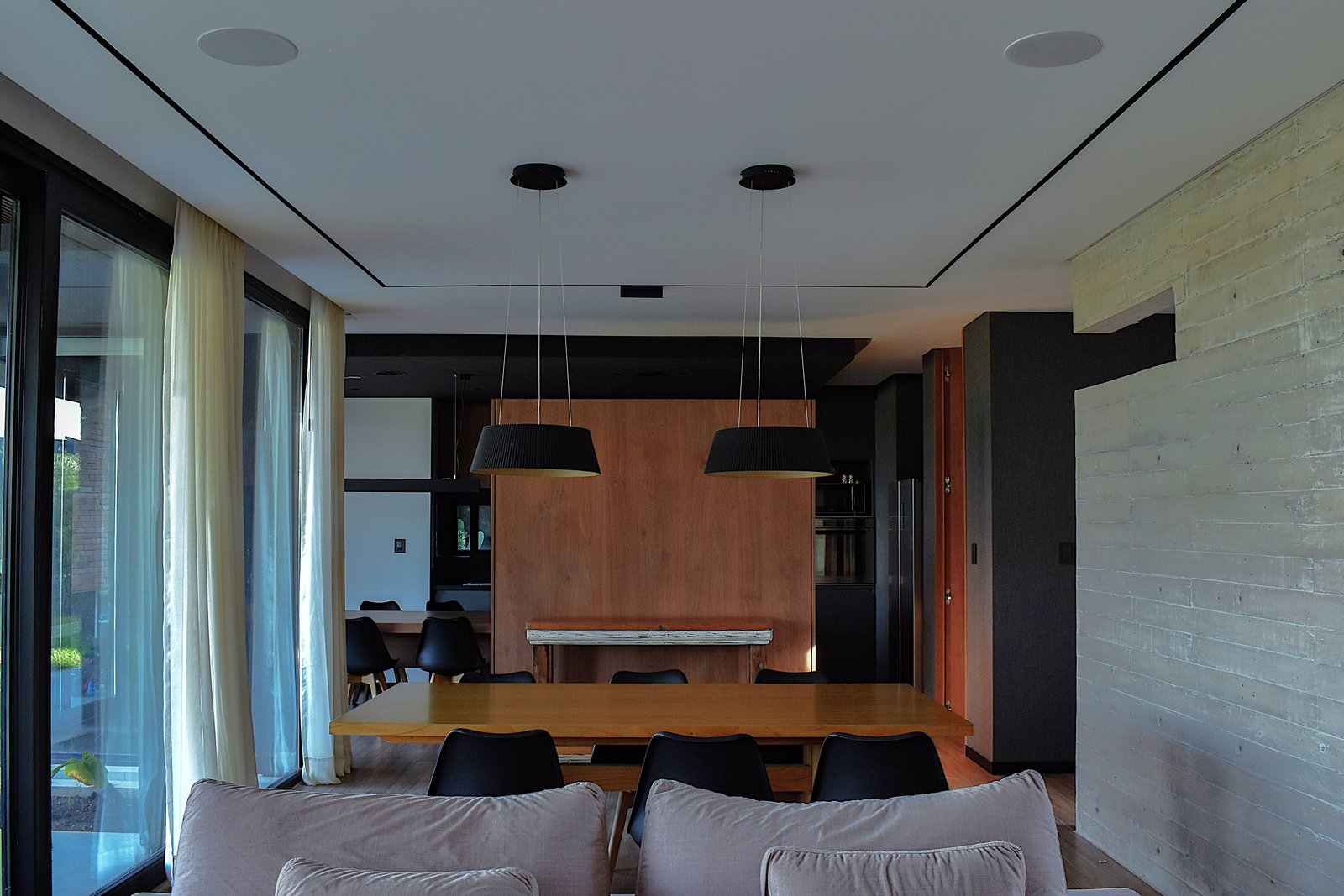 Comedor moderno con mesa de madera y luces cónicas colgantes — proyecto CASA HC, por Daniel Daniele - Oficina de Arquitectura, en Canning