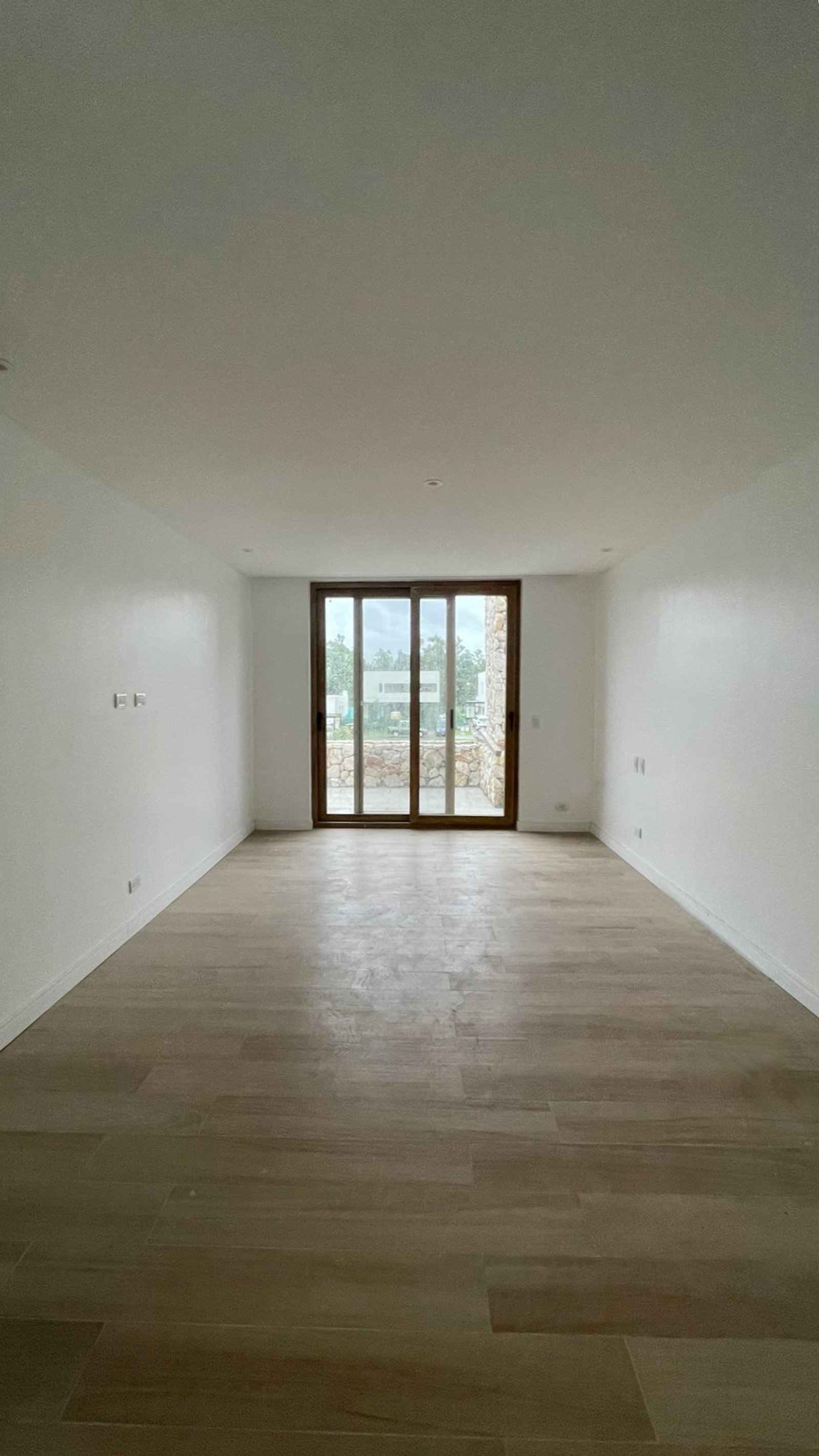 Sala de estar moderna y vacía con gran puerta corrediza de vidrio y piso de madera — proyecto Casa ER , por Hermann Arquitectos, en Arribeños 1611