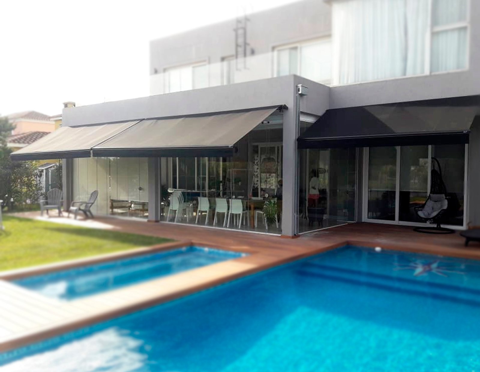 área de piscina moderna com deck de madeira e pergolado — projeto Toldo Brazos Invisibles, por ToldosYa