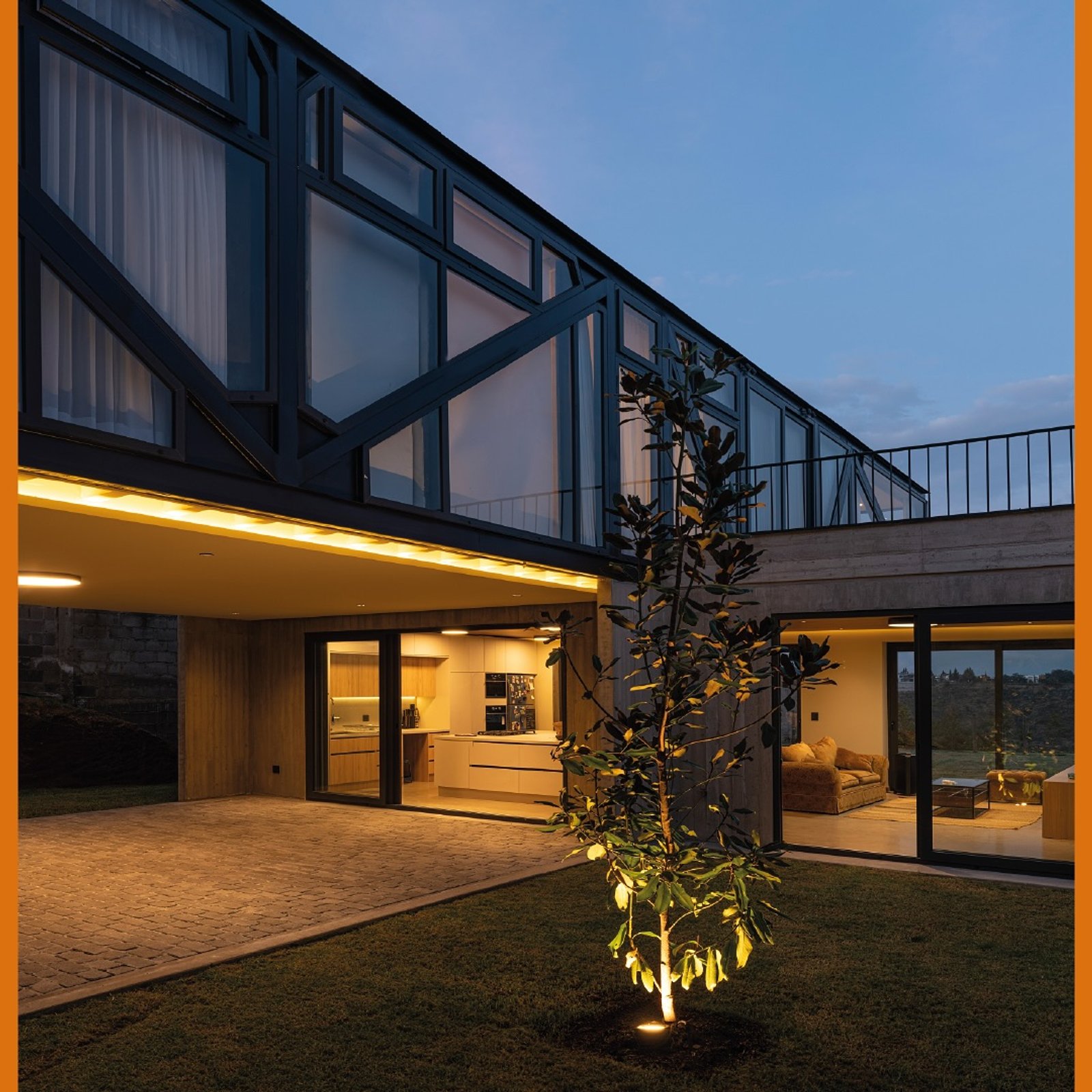 fachada moderna com amplas janelas e iluminação noturna quente — projeto Casa Lumbre, por MUCHTEK, em Tumbaco