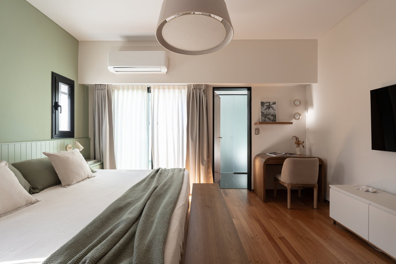 Dormitorio moderno con escritorio, pared verde y luz colgante — proyecto Felipe Vallese, por Estudio BDM, en Flores