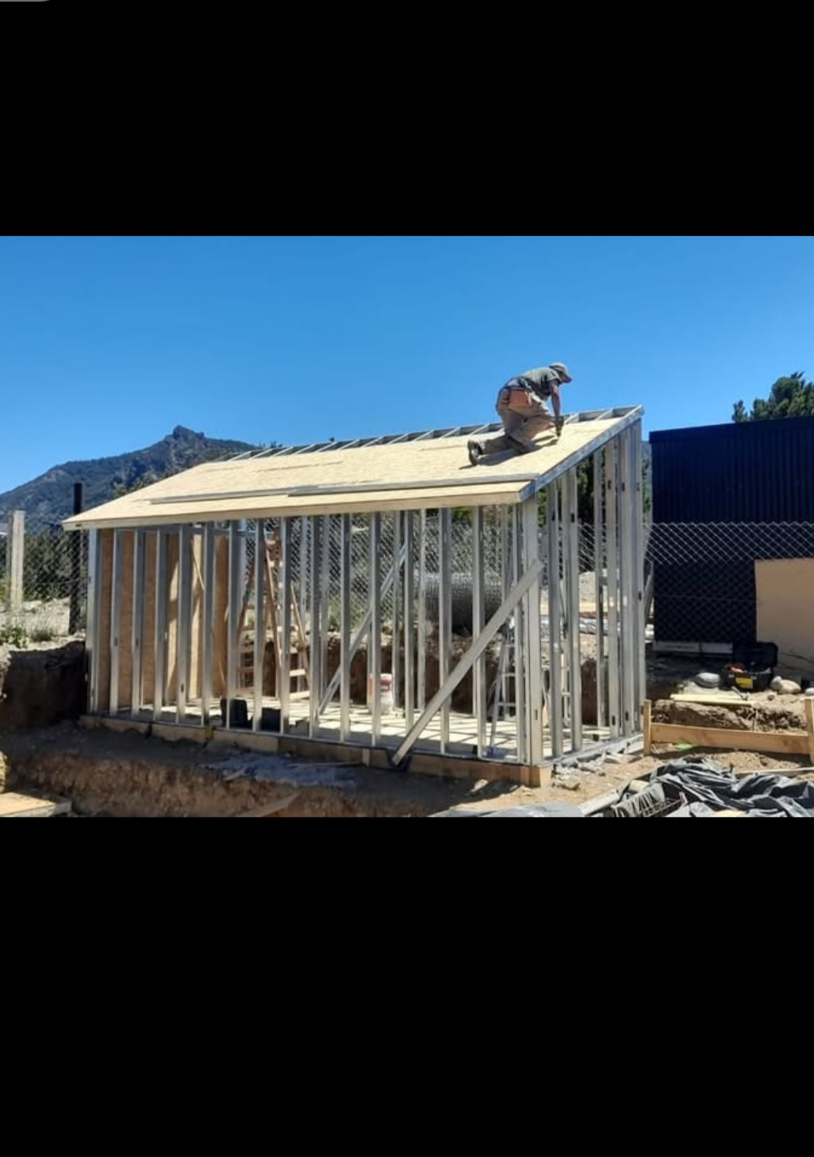 obra de cobertizo metálico con persona trabajando en el techo — proyecto Depósito y taller en lomas de cauquen, por LP reformas y refacciones , en San Carlos de Bariloche