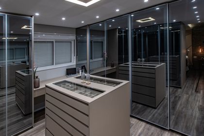 Showroom minimalista con isla central, espejos y mobiliario gris — proyecto Duo Morumbi, por Pricila Dalzochio