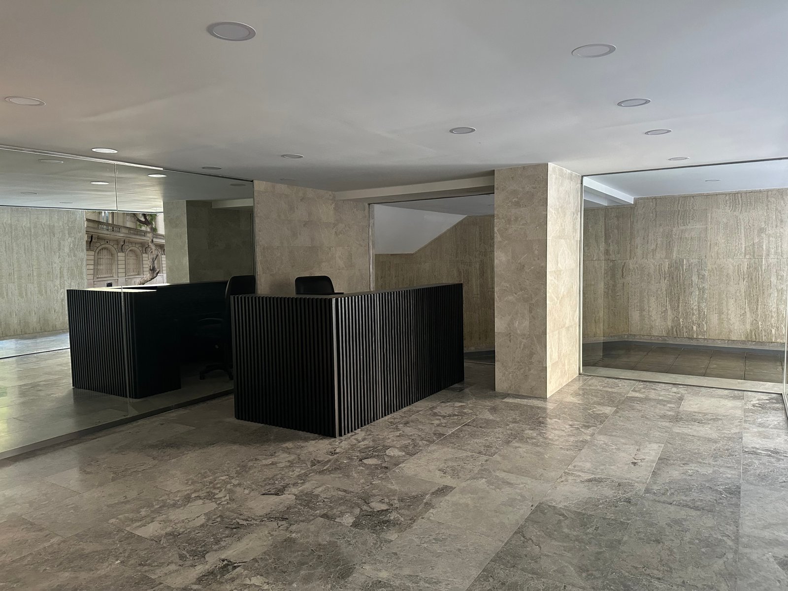 Recepción moderna con pisos de mármol y escritorios de madera — proyecto SAN MARTÍN DE TOURS, por ESTUDIO TEZ, en Palermo